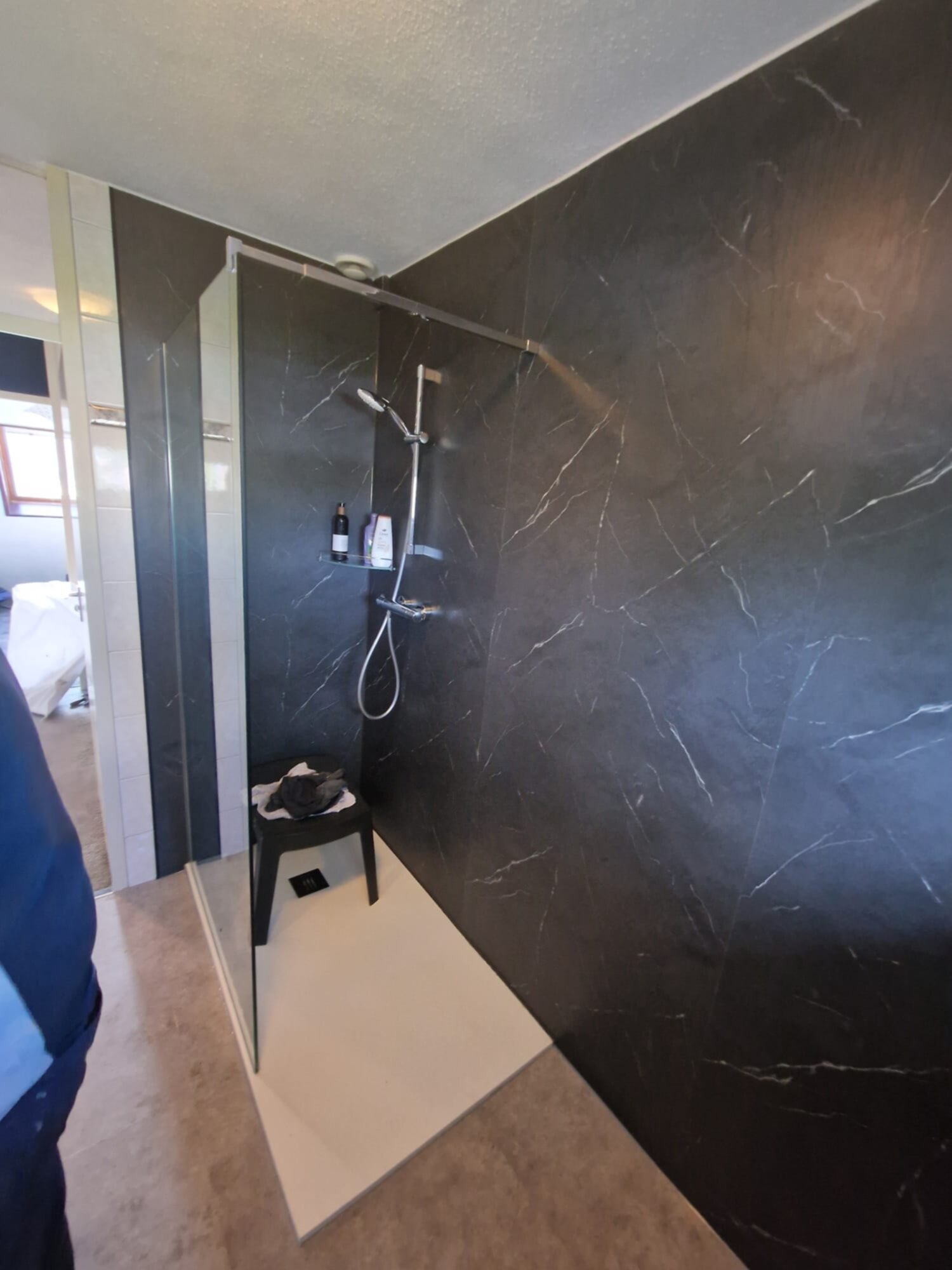 Douchecellen met zwarte marmeren wand en witte betegelde vloer