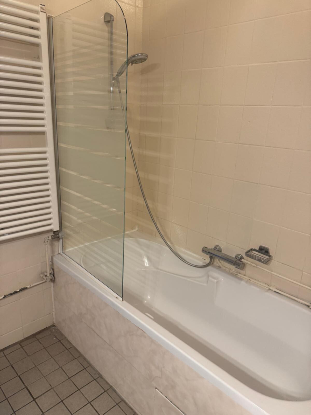 Badkamer met witte tegelwand en glazen douchecabine