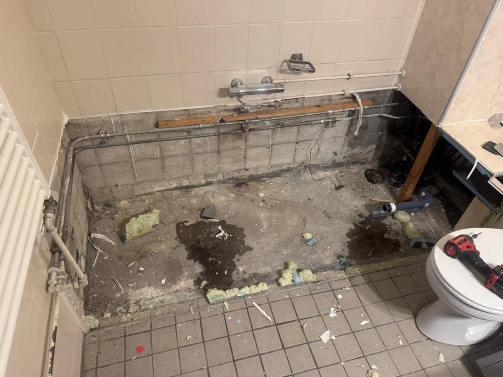 Slechte staat badkamer met oude betegeling en rioleringswerkzaamheden