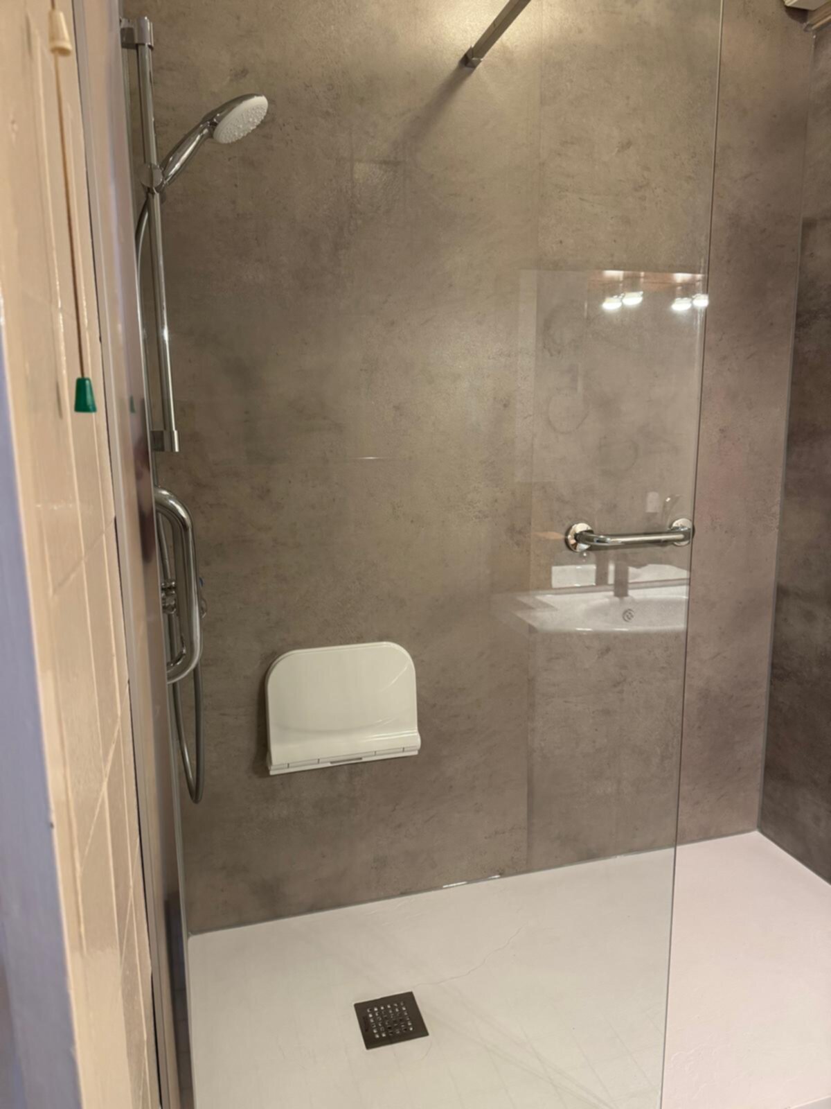 Douchecabine met glazen deur, grijs betegelde wand en witte vloer
