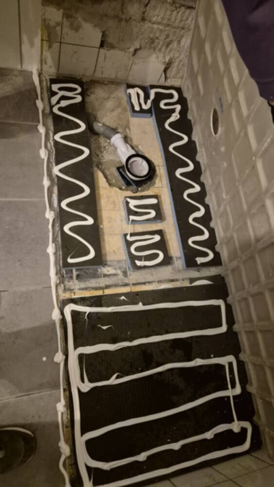 Badkamer vloer renovatie met verwarmingselementen en tegelwerk in aanbouw