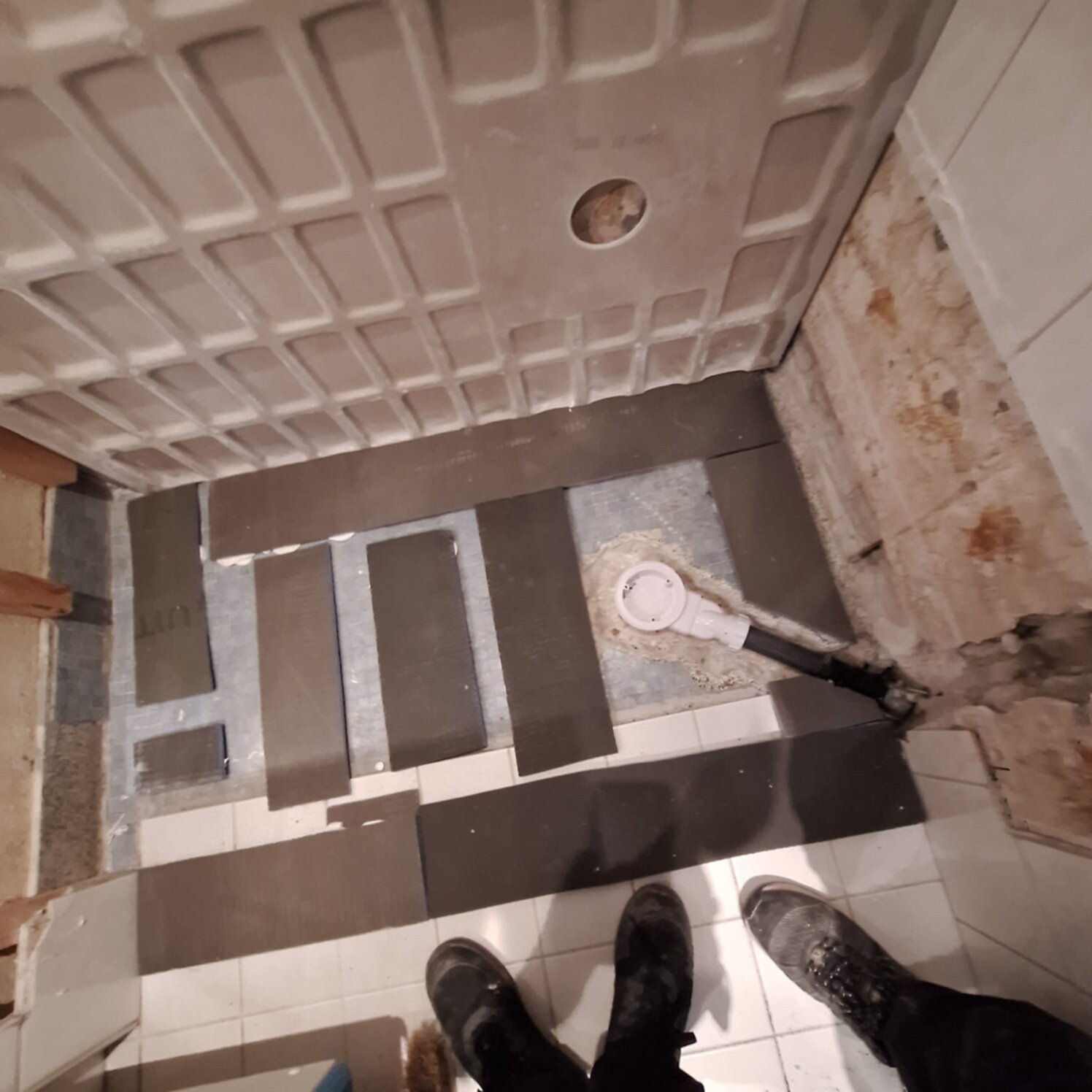 Badkamer renovatie, betegelde vloer in aanbouw, grijs en wit