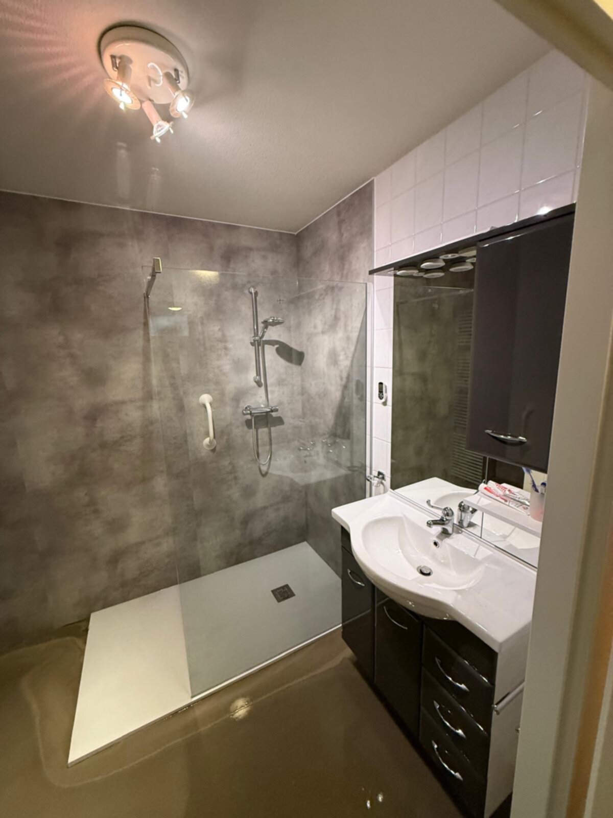 Moderne badkamer met grijze wanden, witte wasbak en zwarte kasten