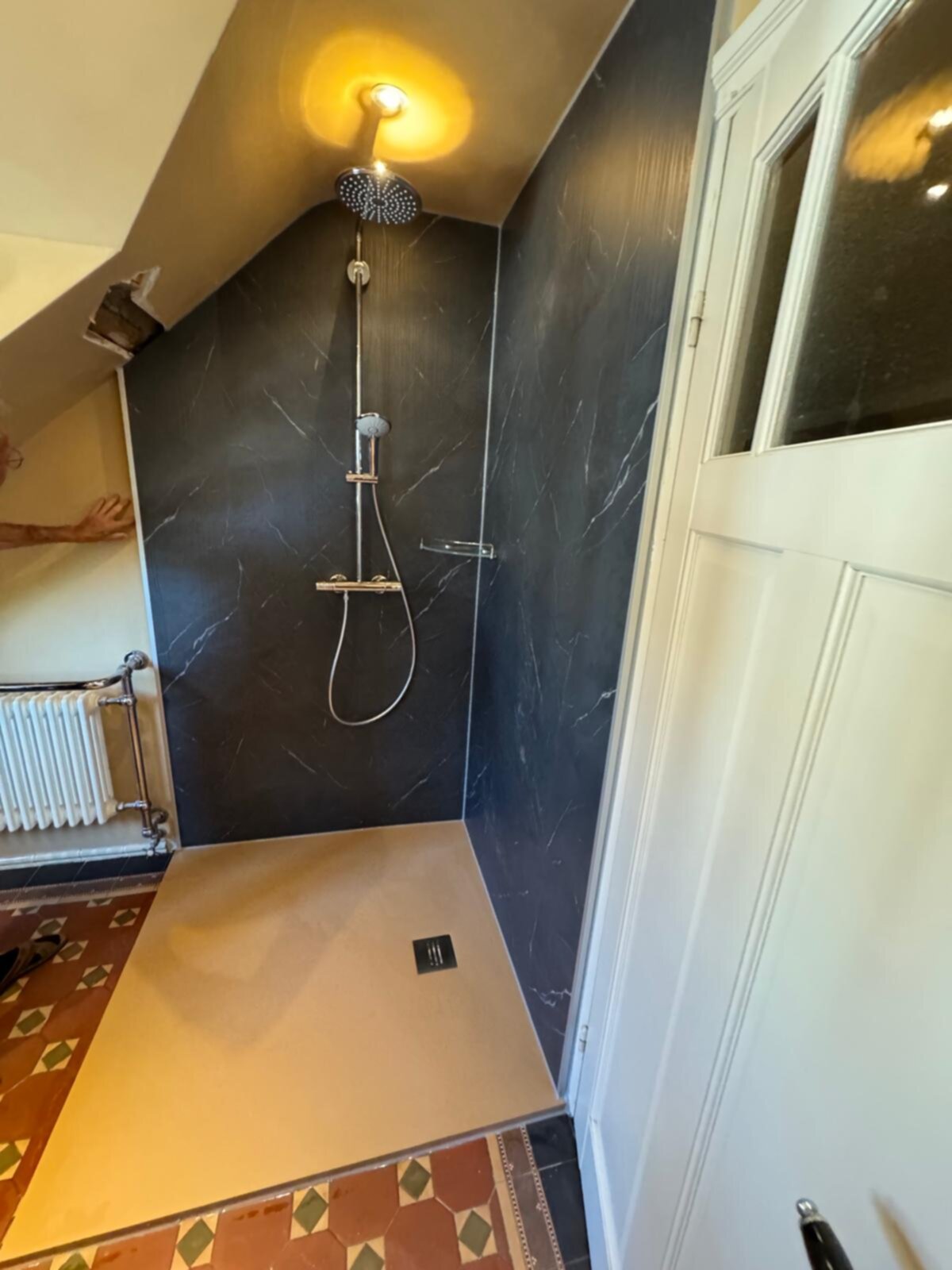 Douche ruimte met zwarte marmeren wanden en beige douchevloer