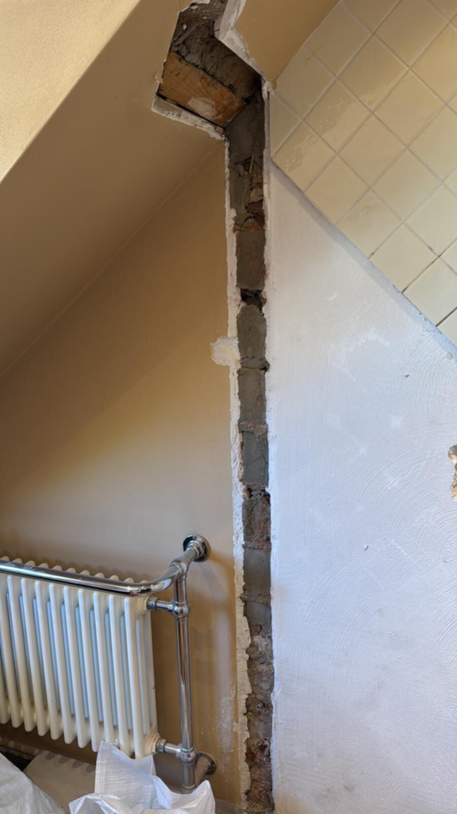 Slecht gemaakte foto van een betegelde muur met een openliggende bakstenen muur