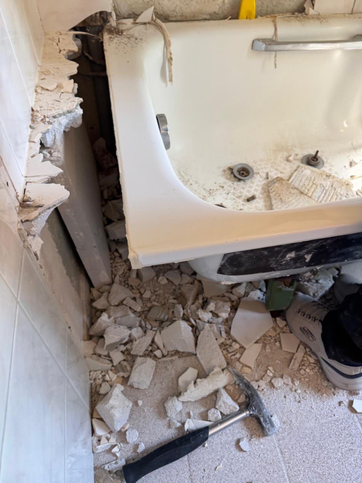 Sloop badkamer met kapotte badkuip en tegelvloer