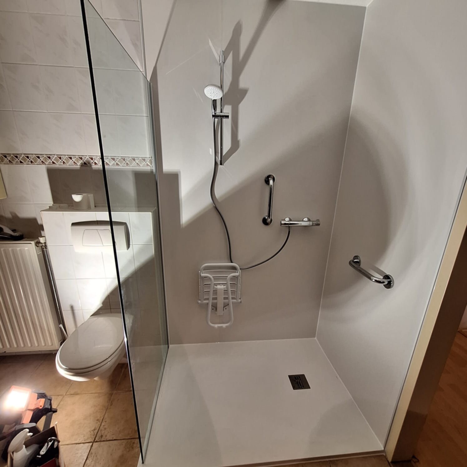 Douchecabine met glazen deur en witte wanden en vloer