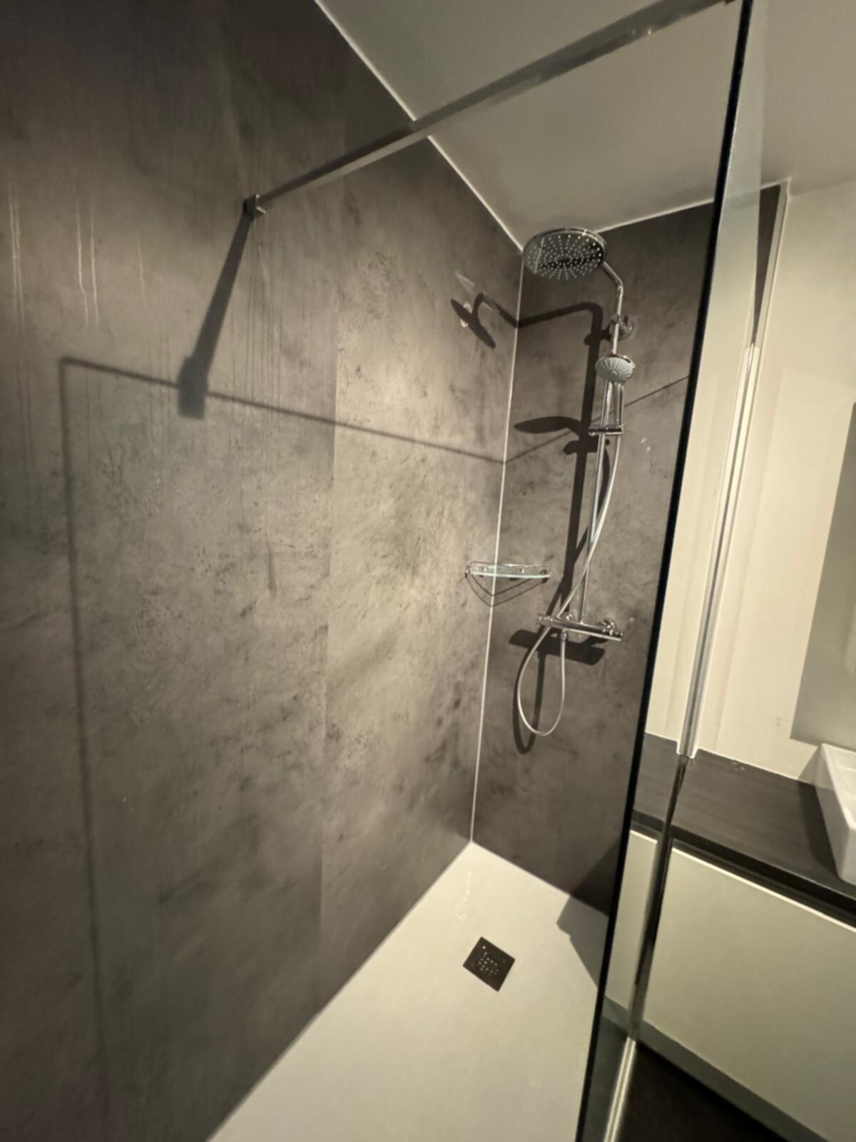 Douche met grijze tegelwanden en witte douchebak