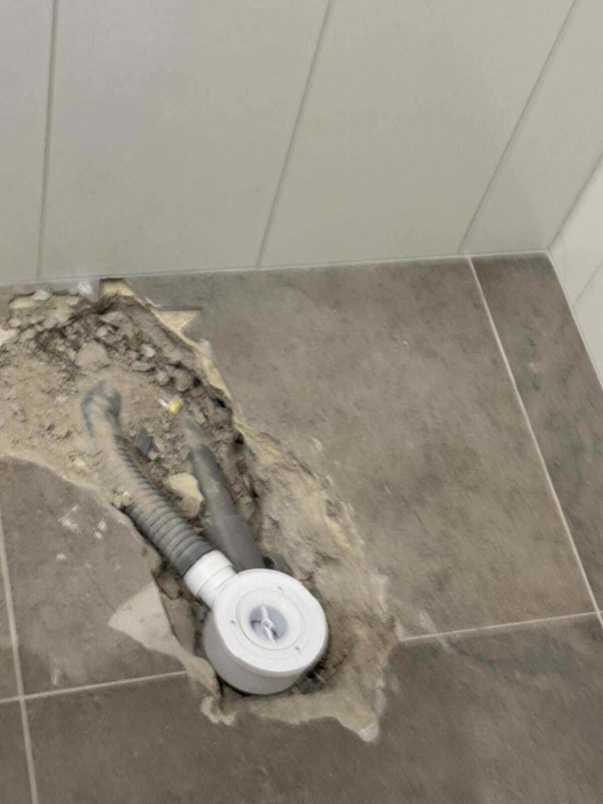 Sleuf in de badkamer vloer met buizen en stop
