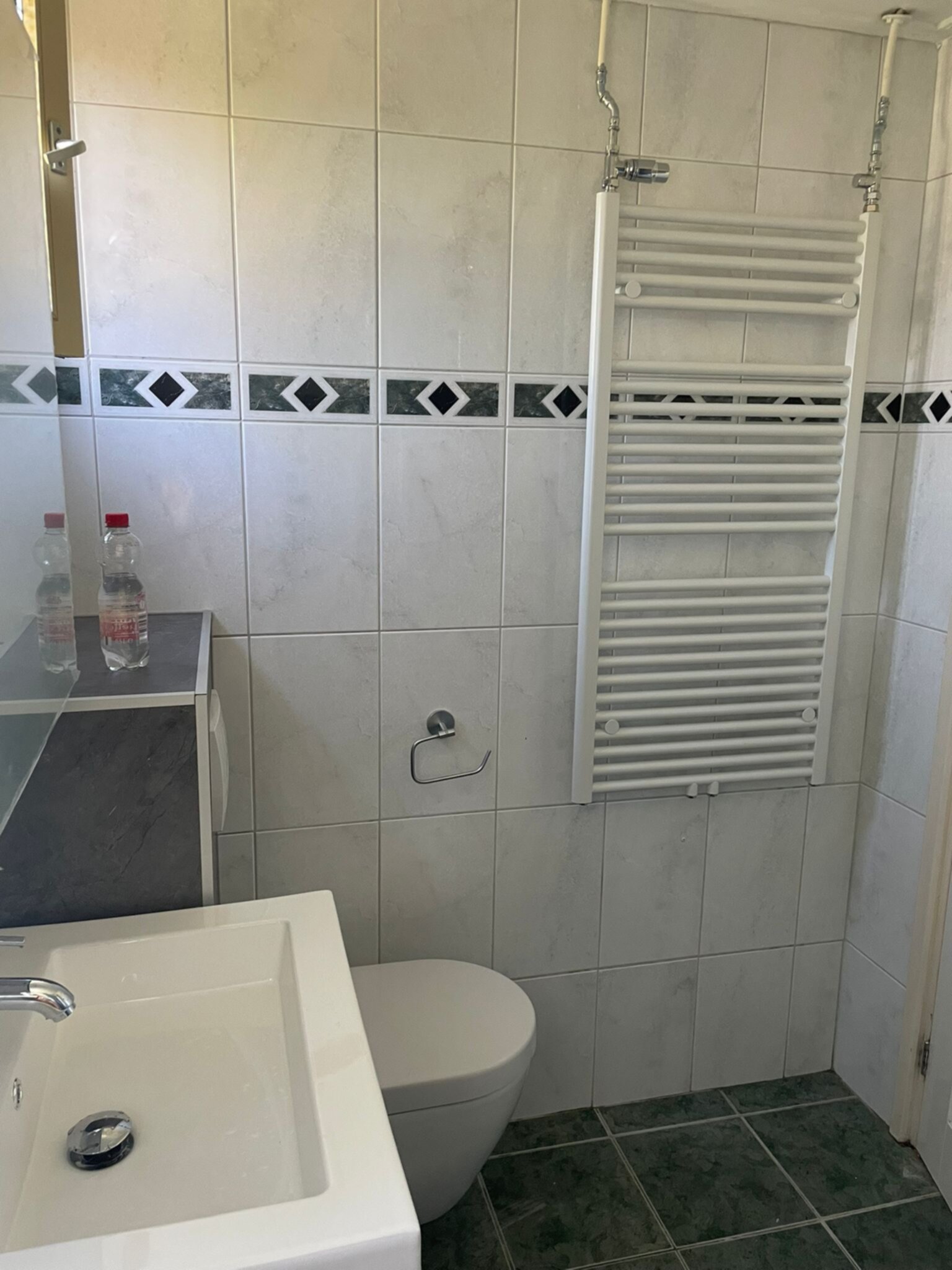 Wit betegelde badkamer met groene vloer en betegelde wanddecoratie