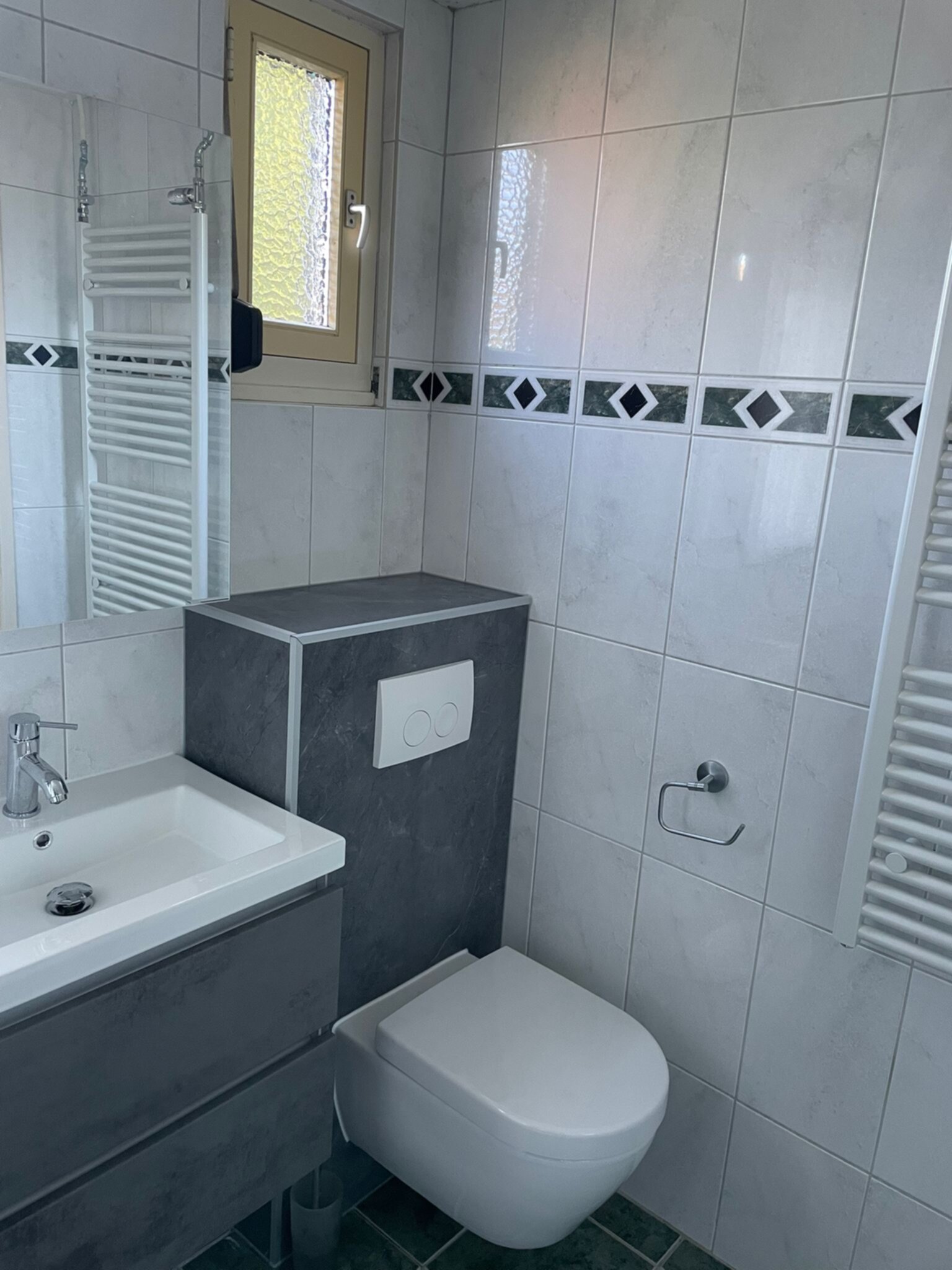 Wit en grijs betegelde badkamer met moderne wastafel en toilet