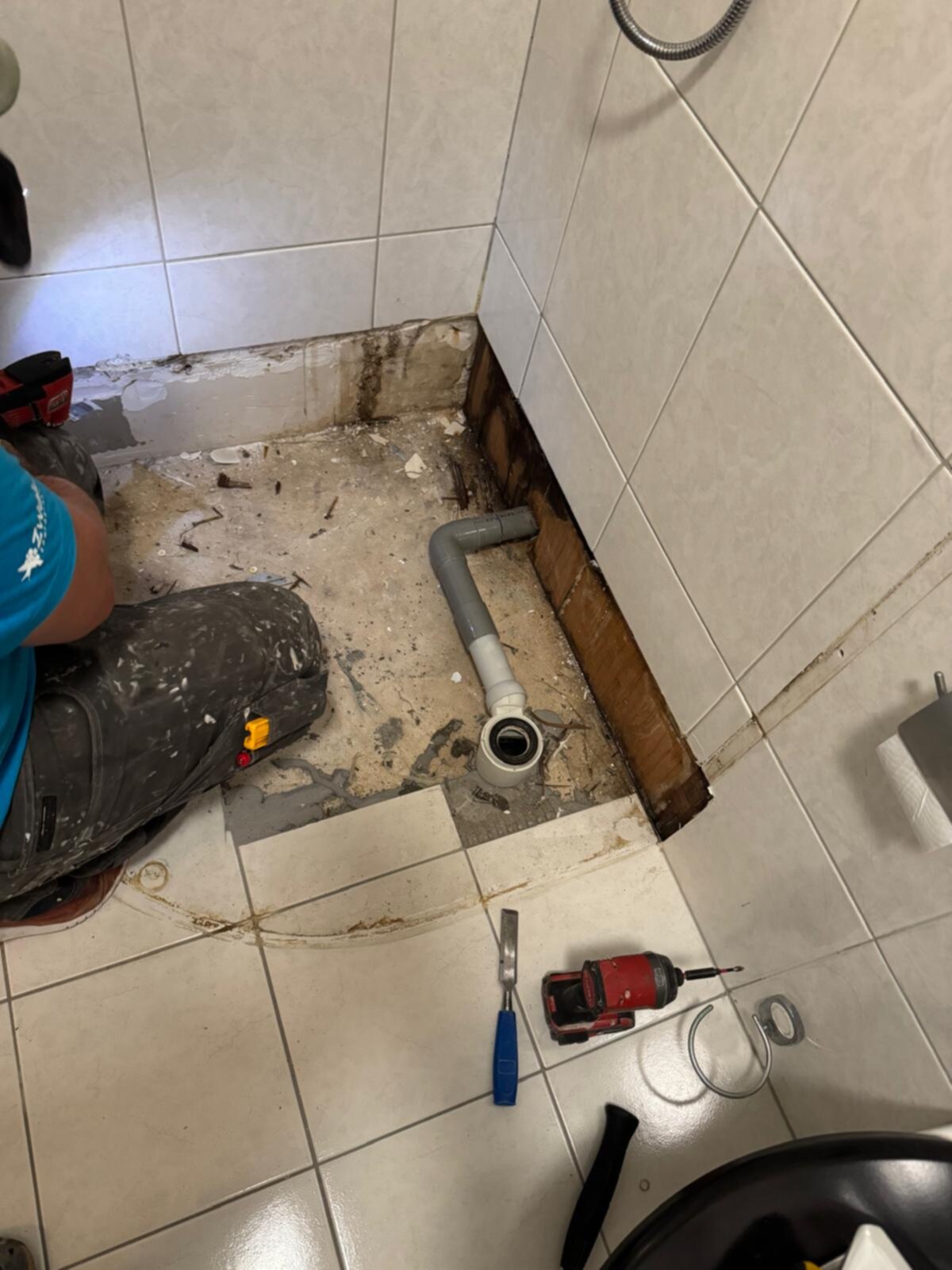 Slecht onderhouden badkamer vloer met kapotte tegel en open leiding