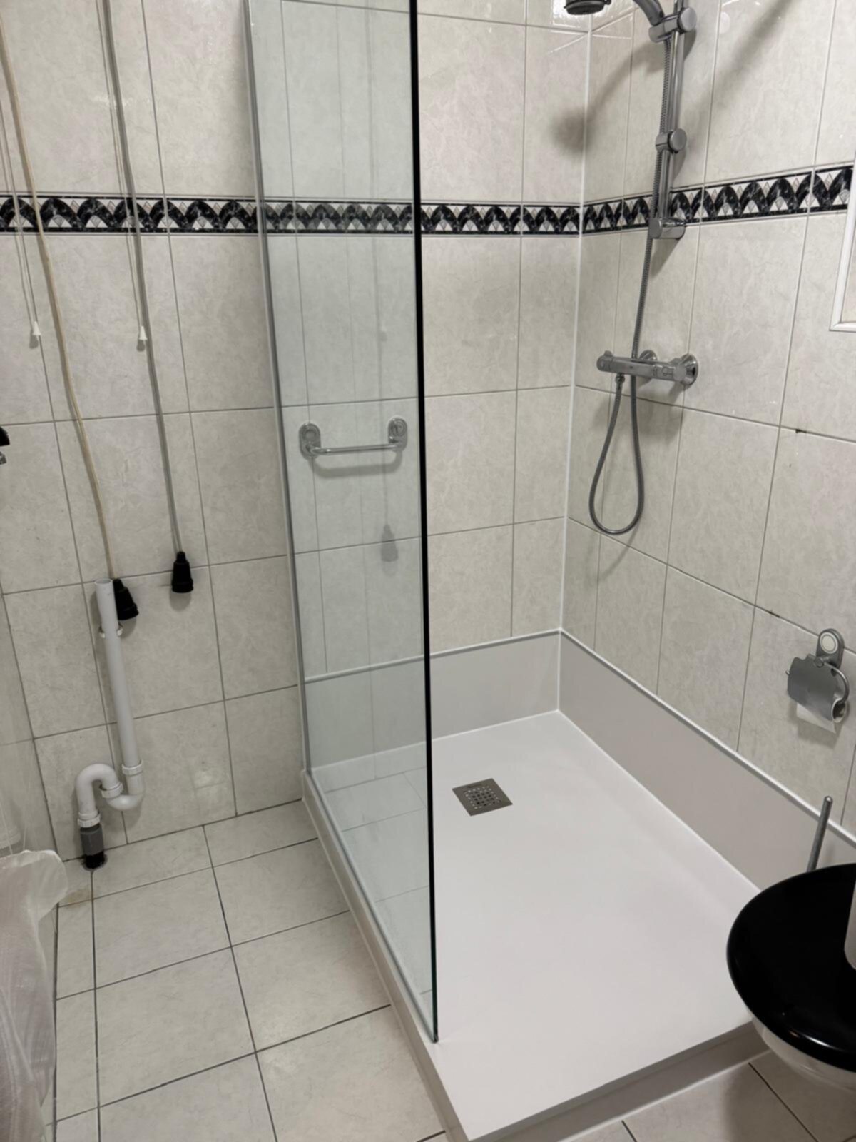 Douchecabine met glazen deur en witte tegelvloer in moderne badkamer