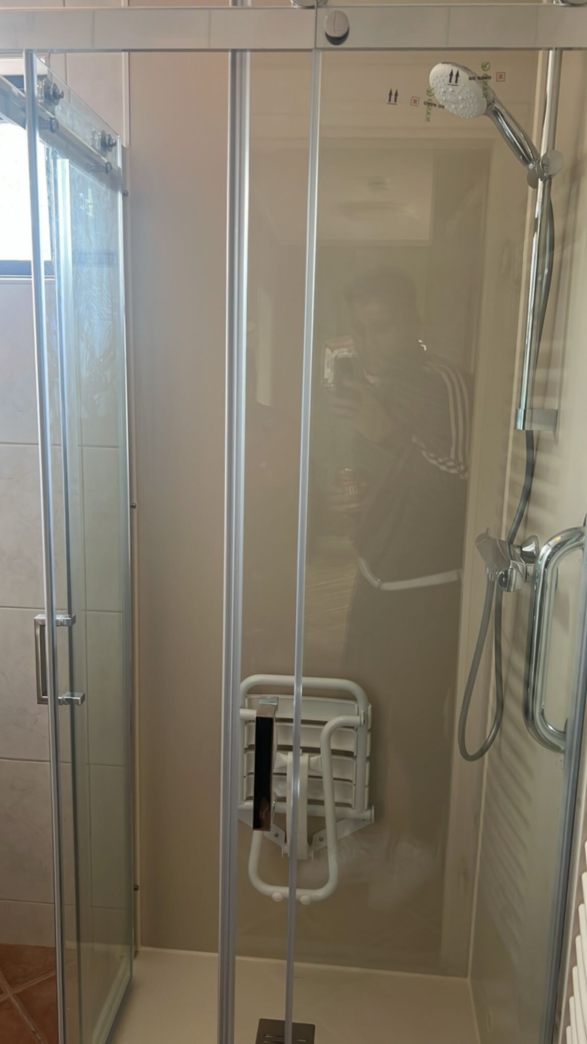Douchecabine met glazen deur en wand, witte en chromen afwerking, betegelde wanden