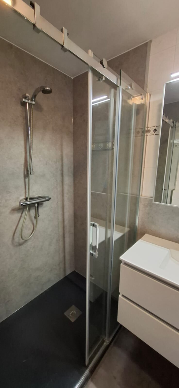 Moderne badkamer met glazen douchecabine en witte wasbak