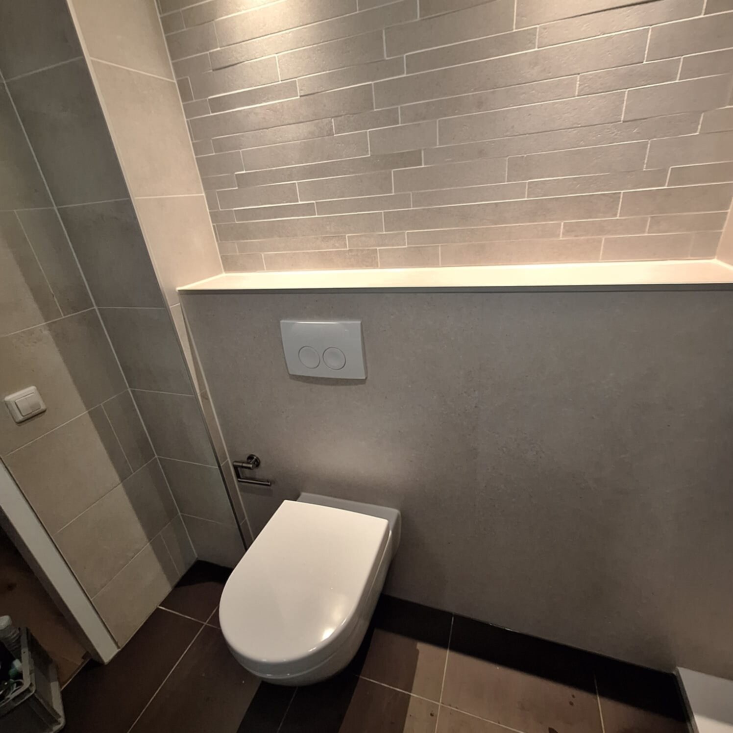 Moderne badkamer met witte toilet en grijze betegeling