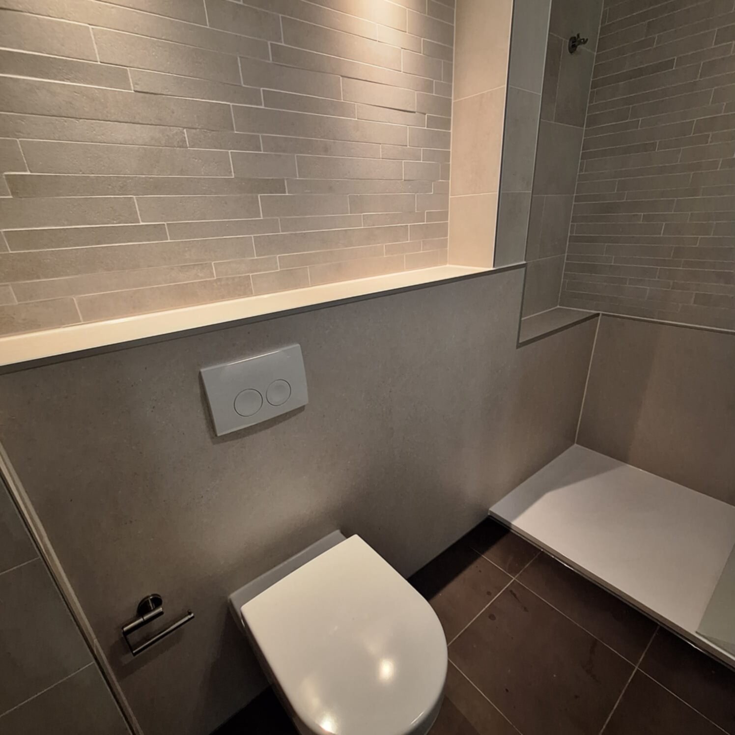 Moderne badkamer met grijze tegelwanden en witte toilet en douche