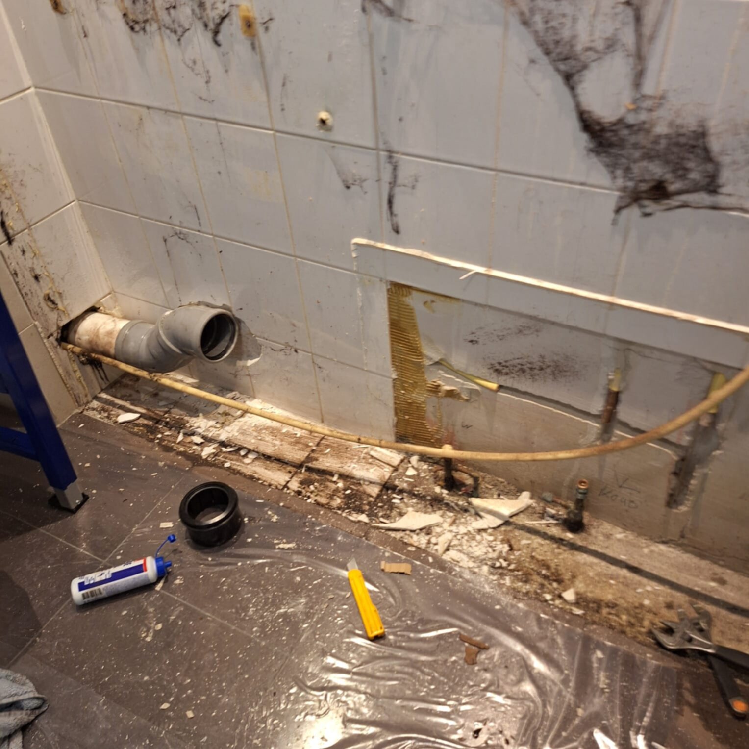 Slechte staat badkamer met marmerlook tegels, gereedschap en materialen voor renovatie