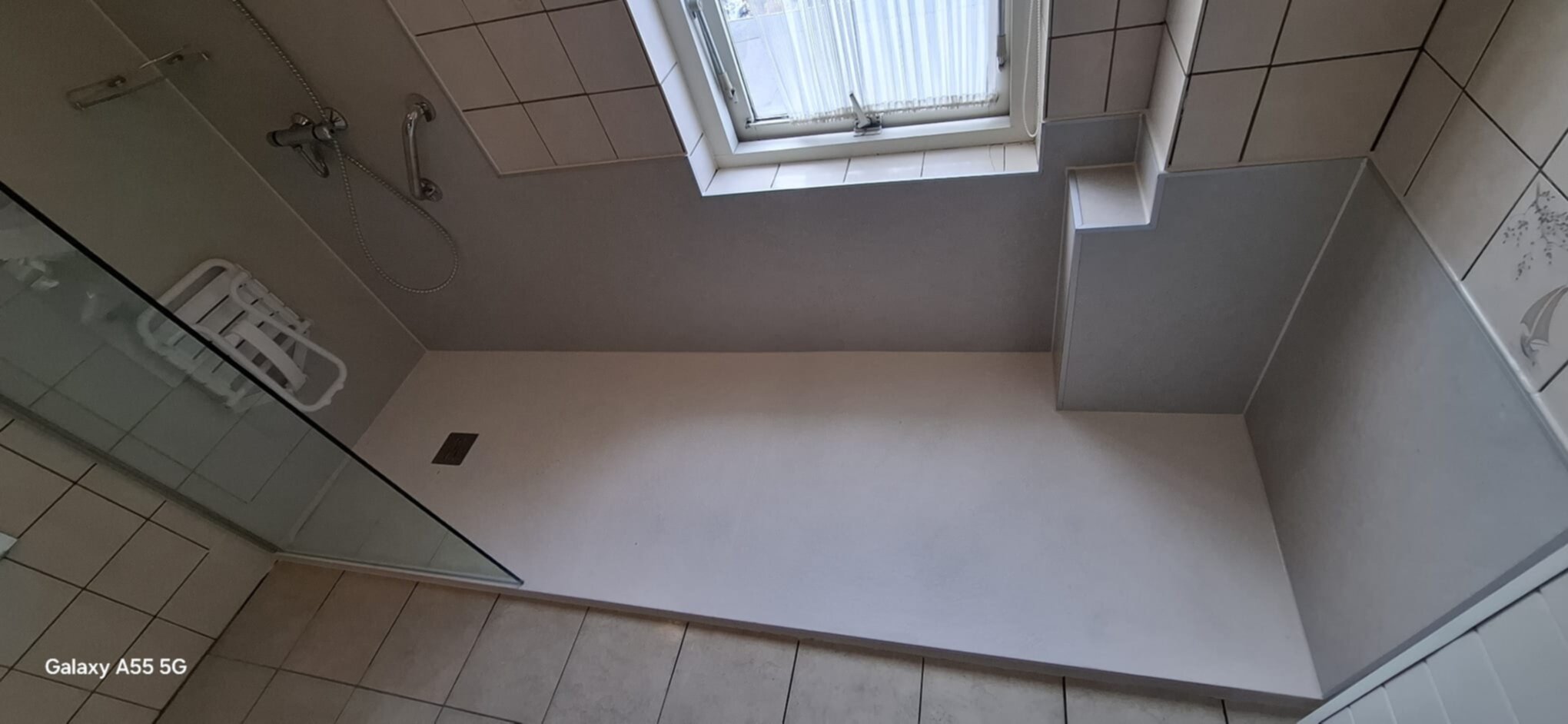 Douche ruimte met witte vloer en beige tegels, klaar voor renovatie.