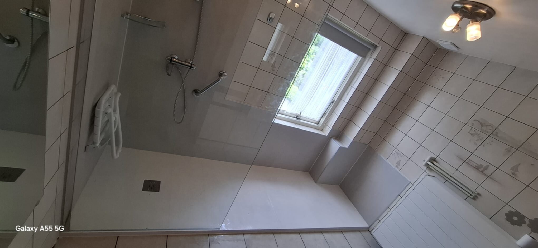 Douchecabine met witte tegels, glazen deur en chroom sanitair