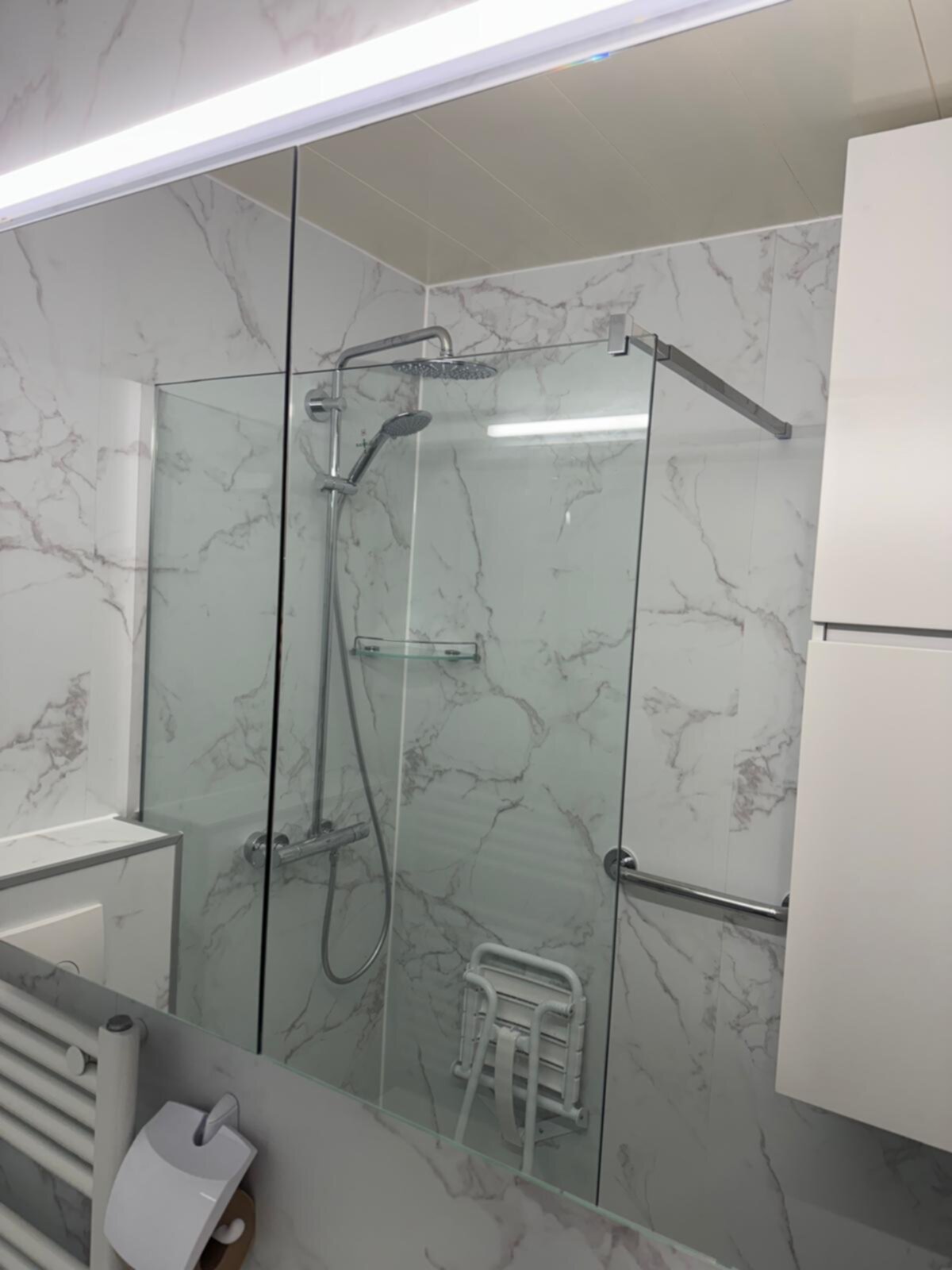 Douche met glazen schuifdeur en marmeren tegelwand in moderne badkamer