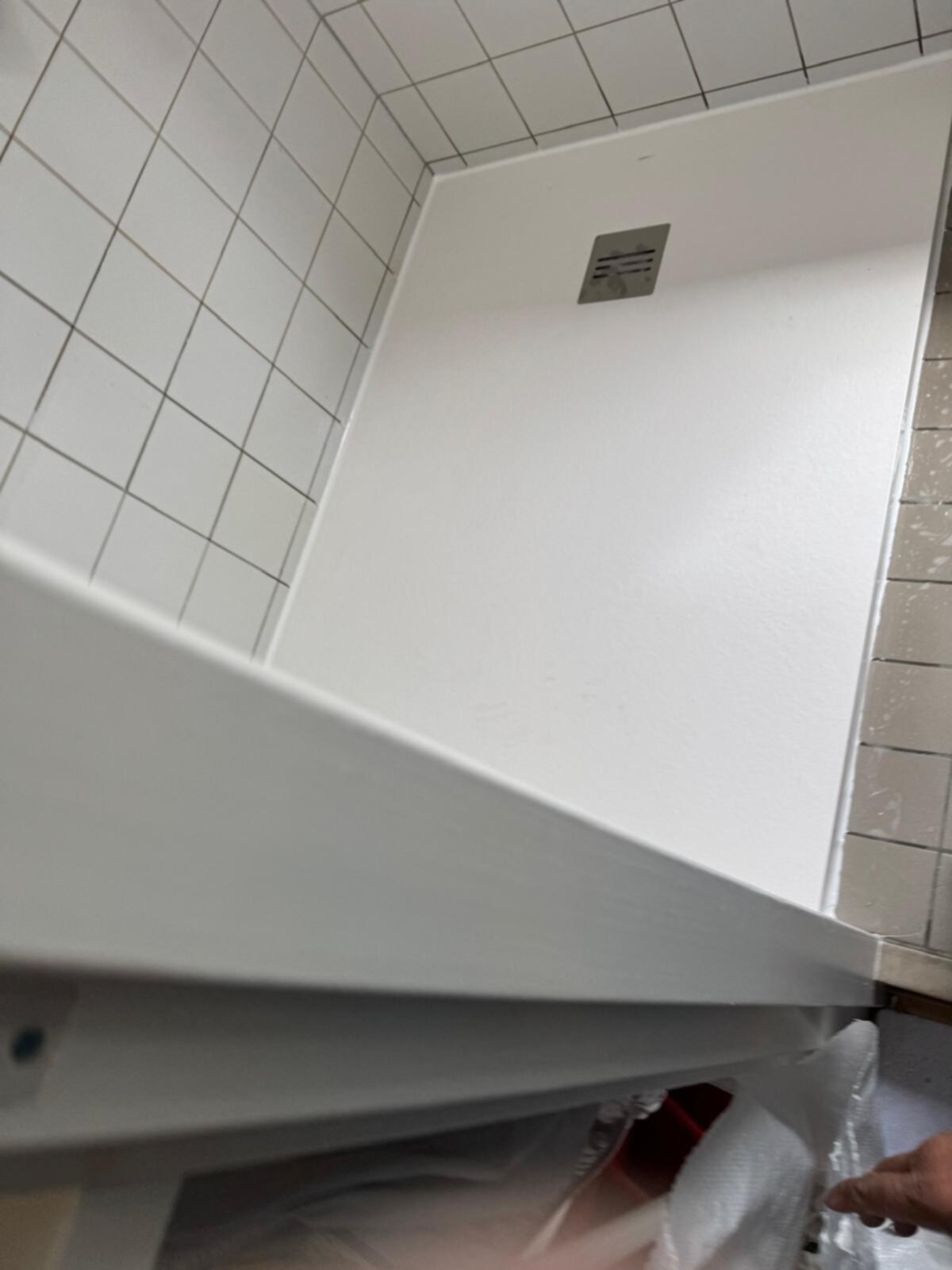 Wit betegelde badkamer met witte douche en betegelde muren