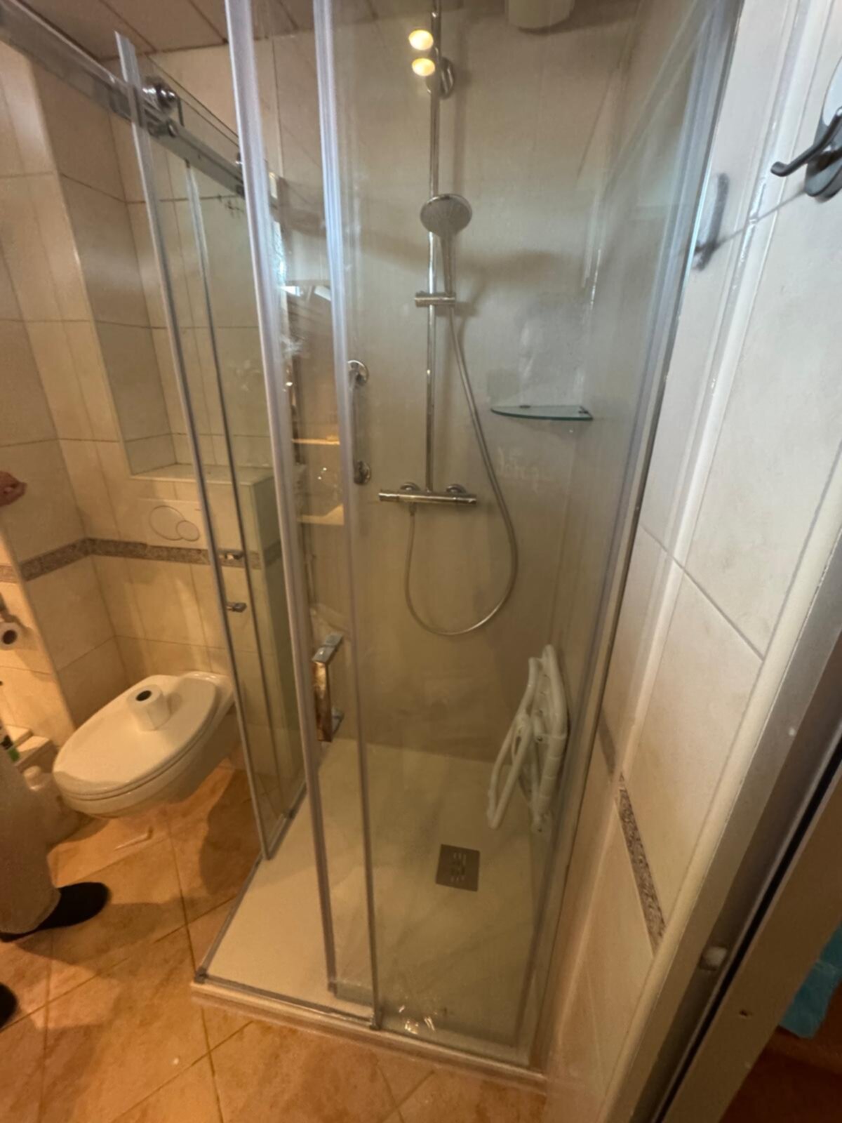Badkamer met douchecabine, toilet en betegelde wanden en vloer