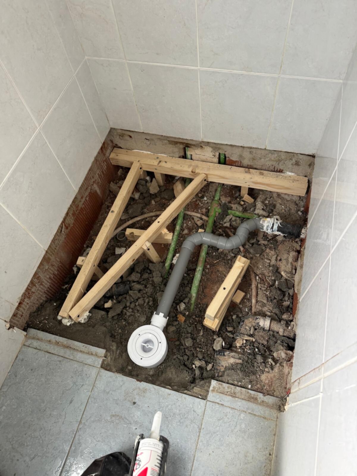 Badkamer renovatie: opengebroken vloer met houten steunconstructie en nieuwe leidingen