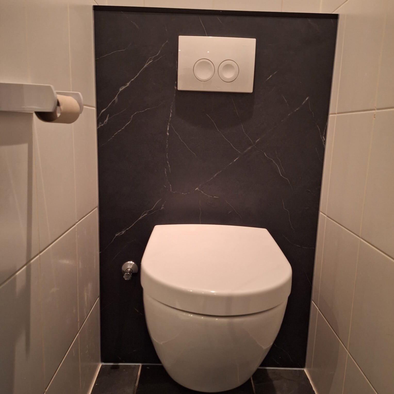 Wit toilet met zwarte marmeren achterwand en witte tegelwanden