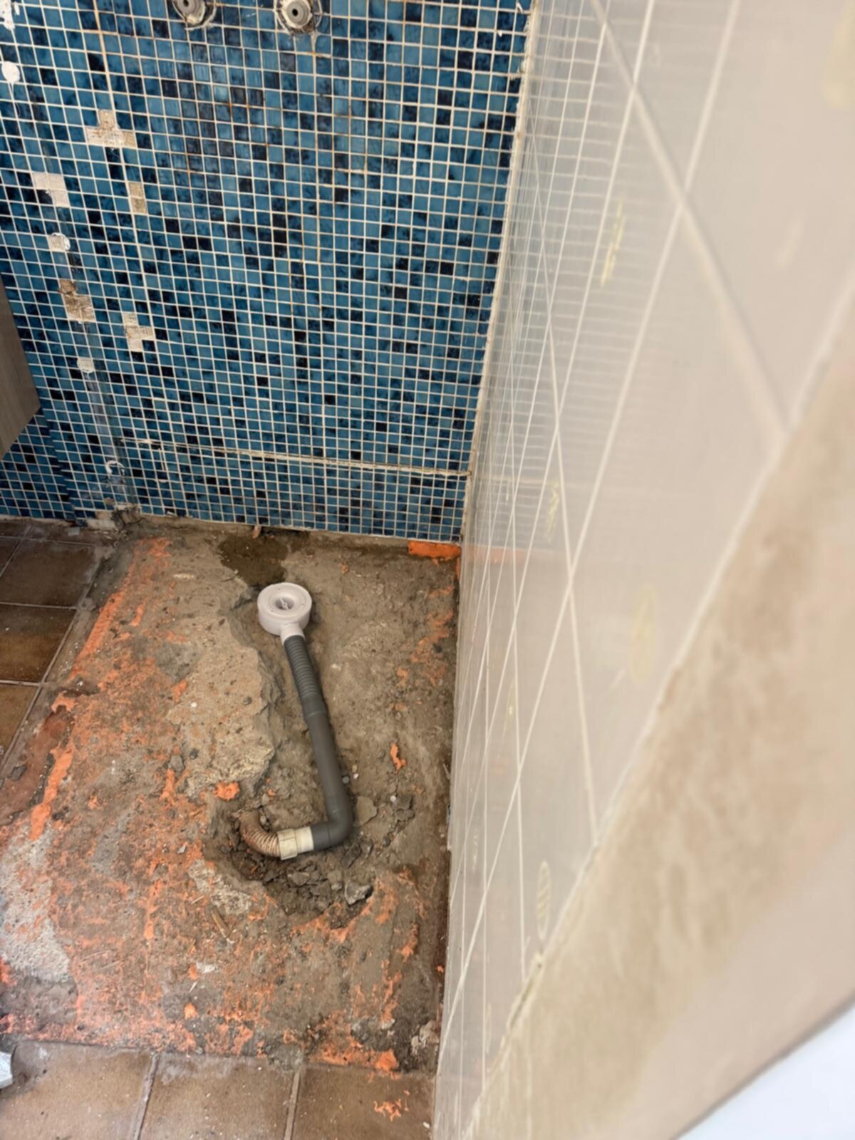Slechte staat badkamer vloer met kapotte tegel en openliggende rioleringsbuis