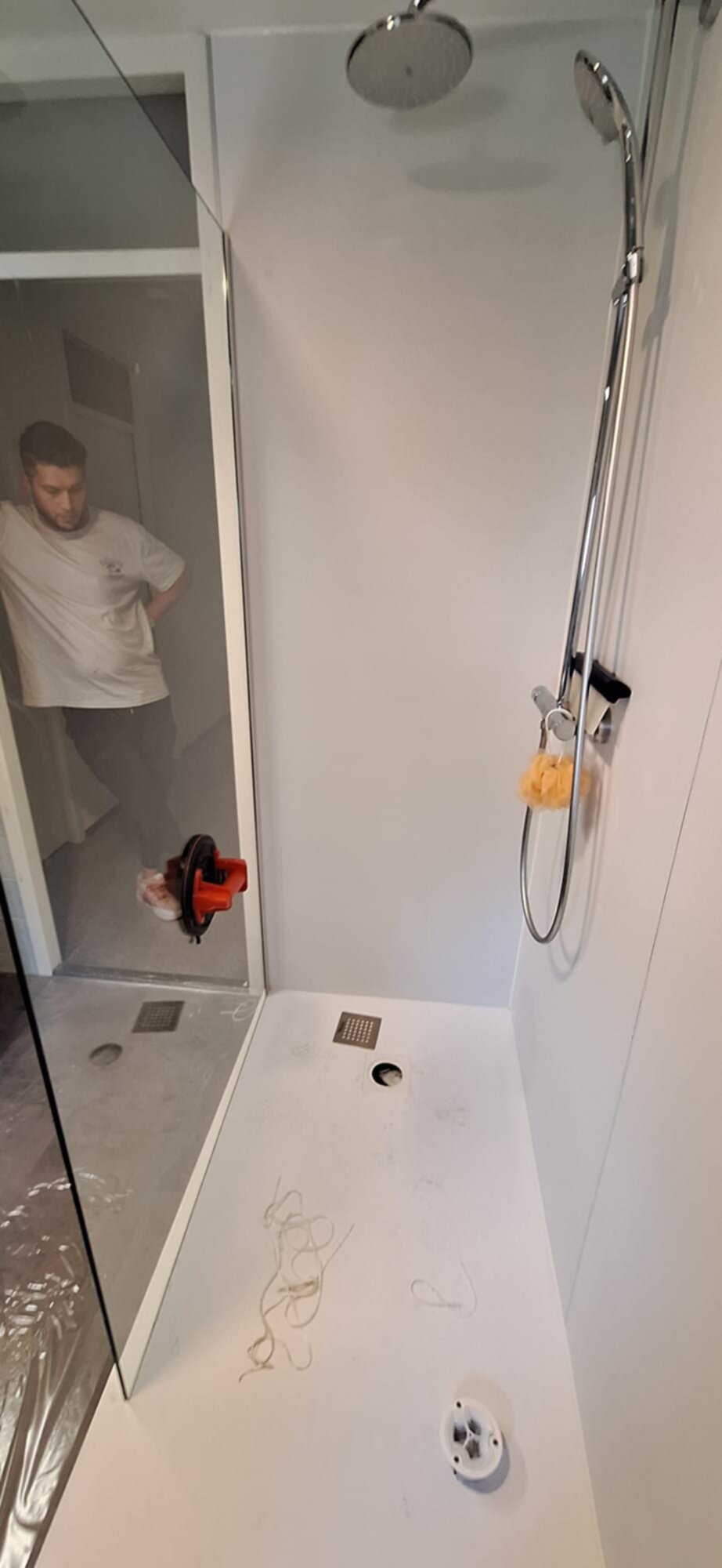 Douchecabine in aanbouw met witte wanden en vloer, chroom douchekraan en -kop