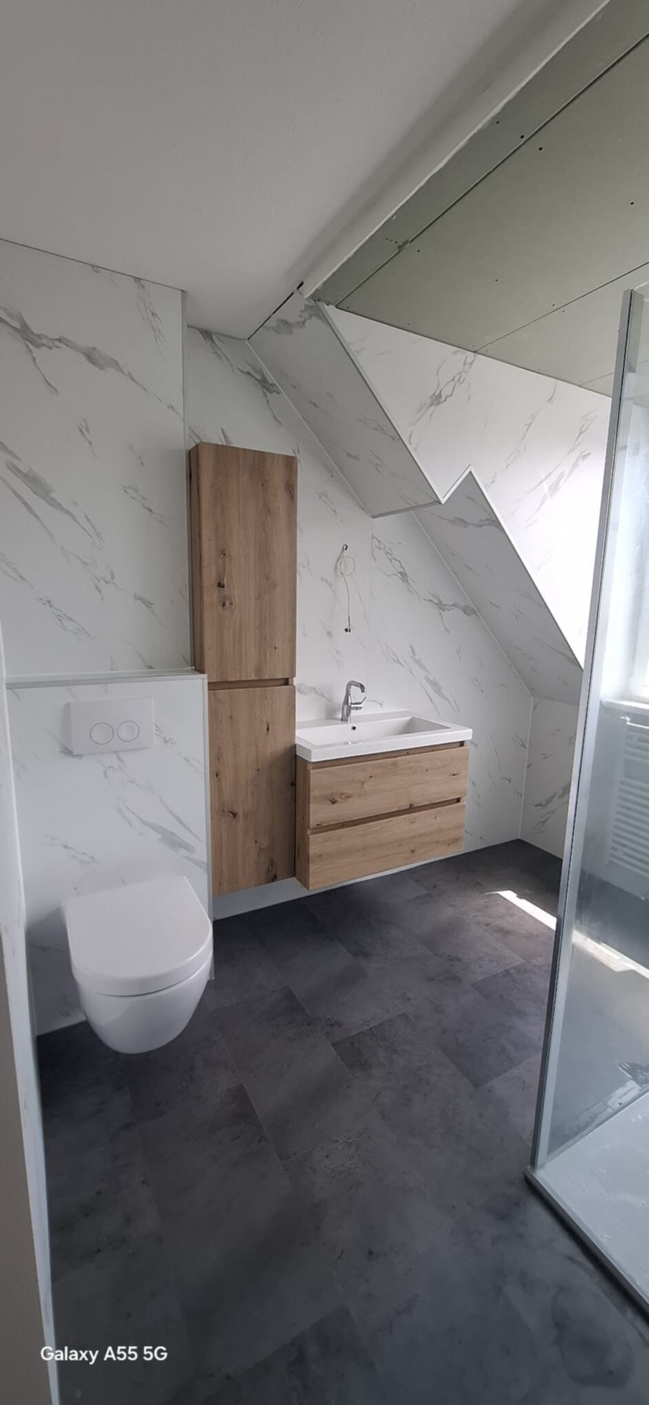 Moderne badkamer met marmerlook tegels, houten meubelen en donkere vloer