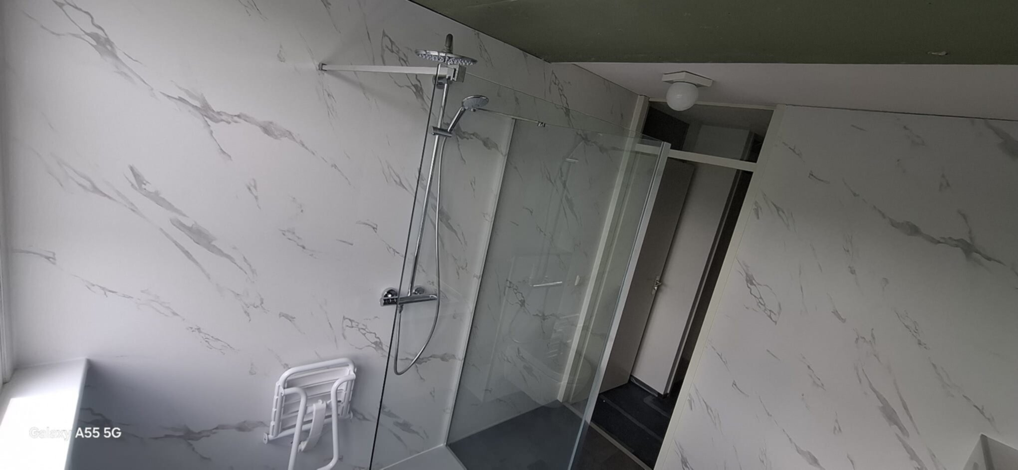 Marmeren badkamer met glazen douchecabine en witte betegeling
