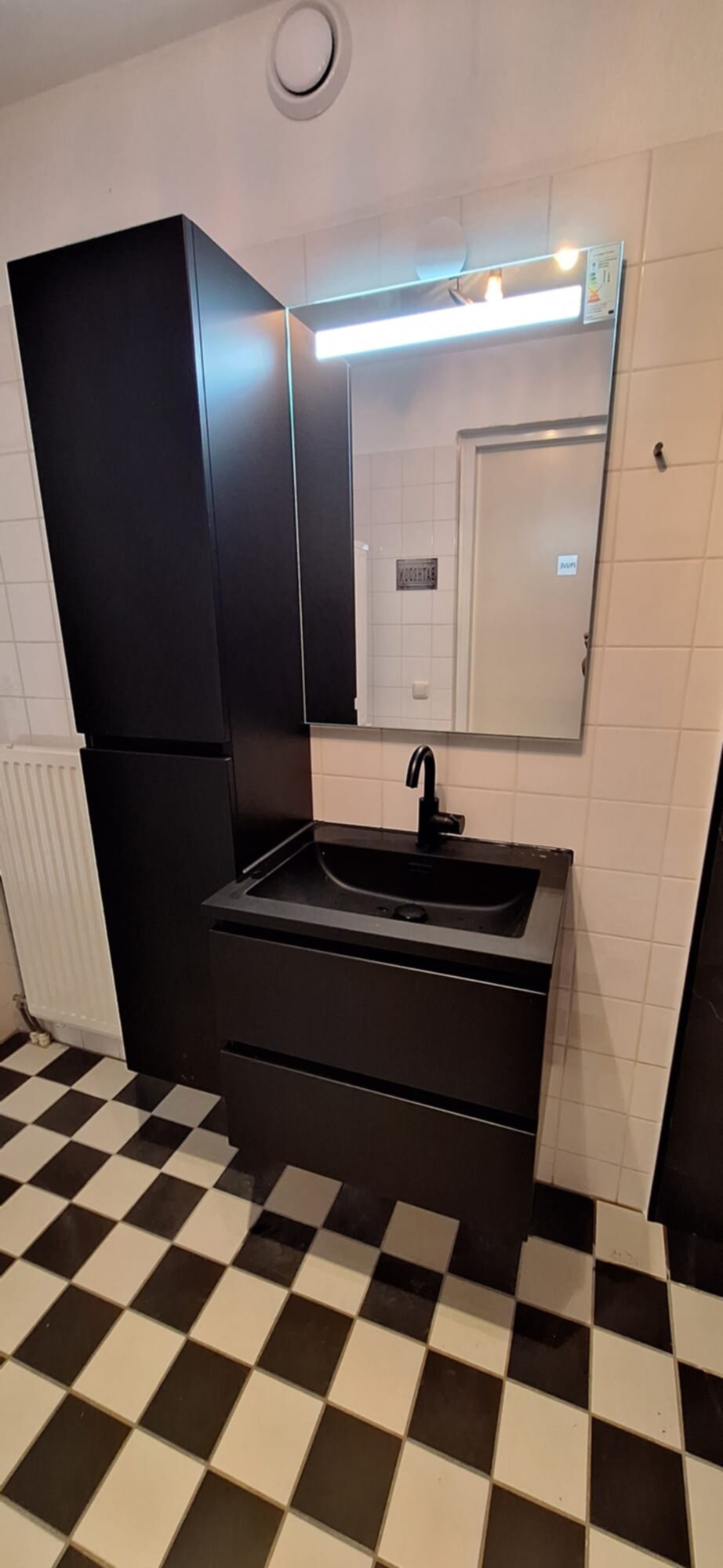 Badkamer met zwarte wastafel en betegelde vloer