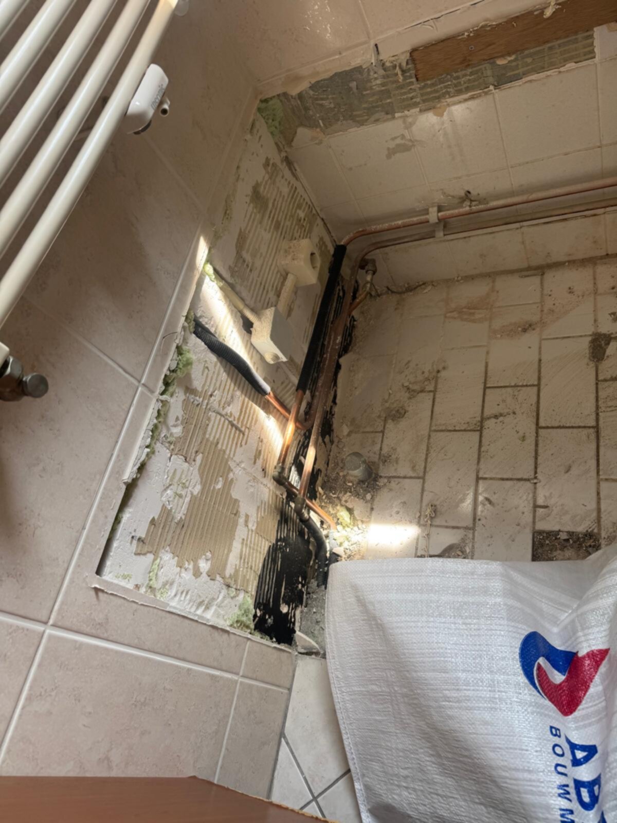 Slechte staat badkamer met kapotte tegels en blootliggende leidingen