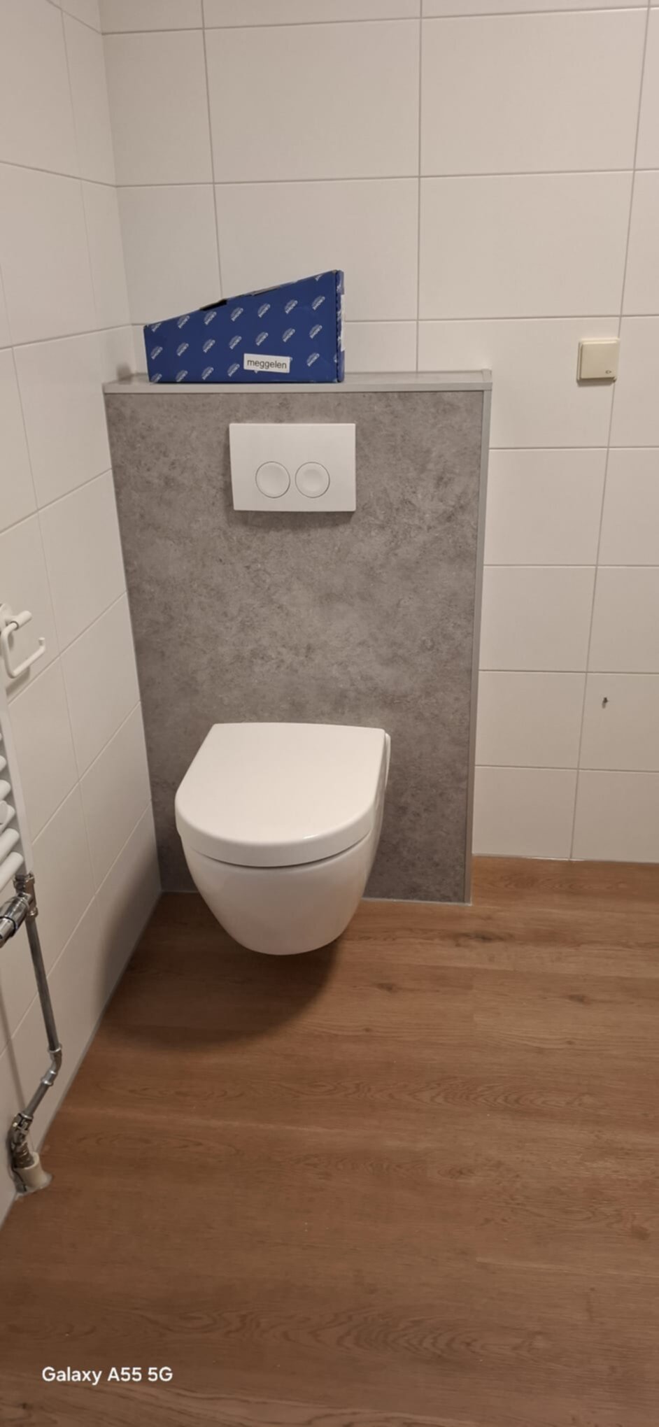 Wit toilet met grijze betegeling en houten vloer in moderne badkamer
