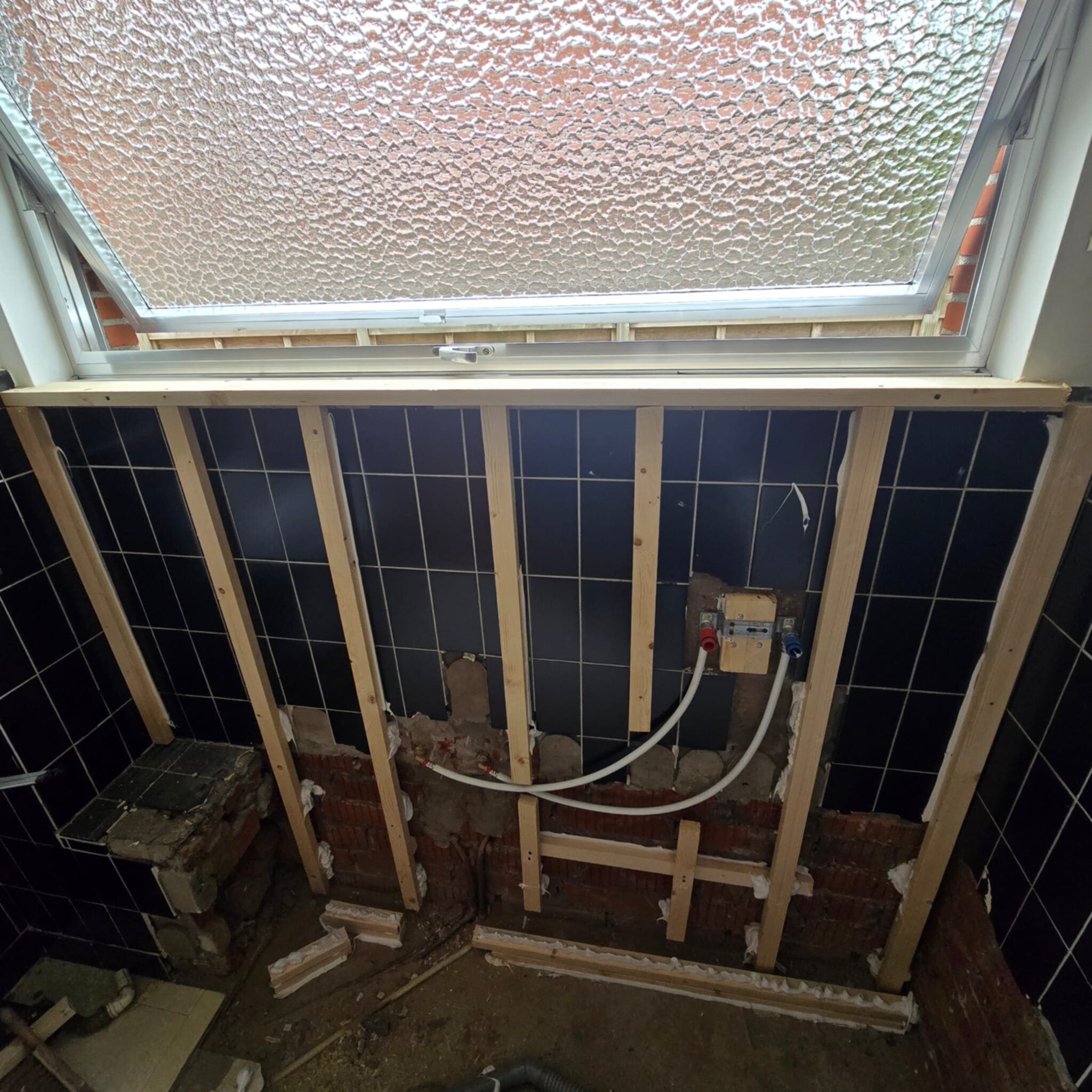 Badkamer onderbouw met houten frame en zwarte tegels