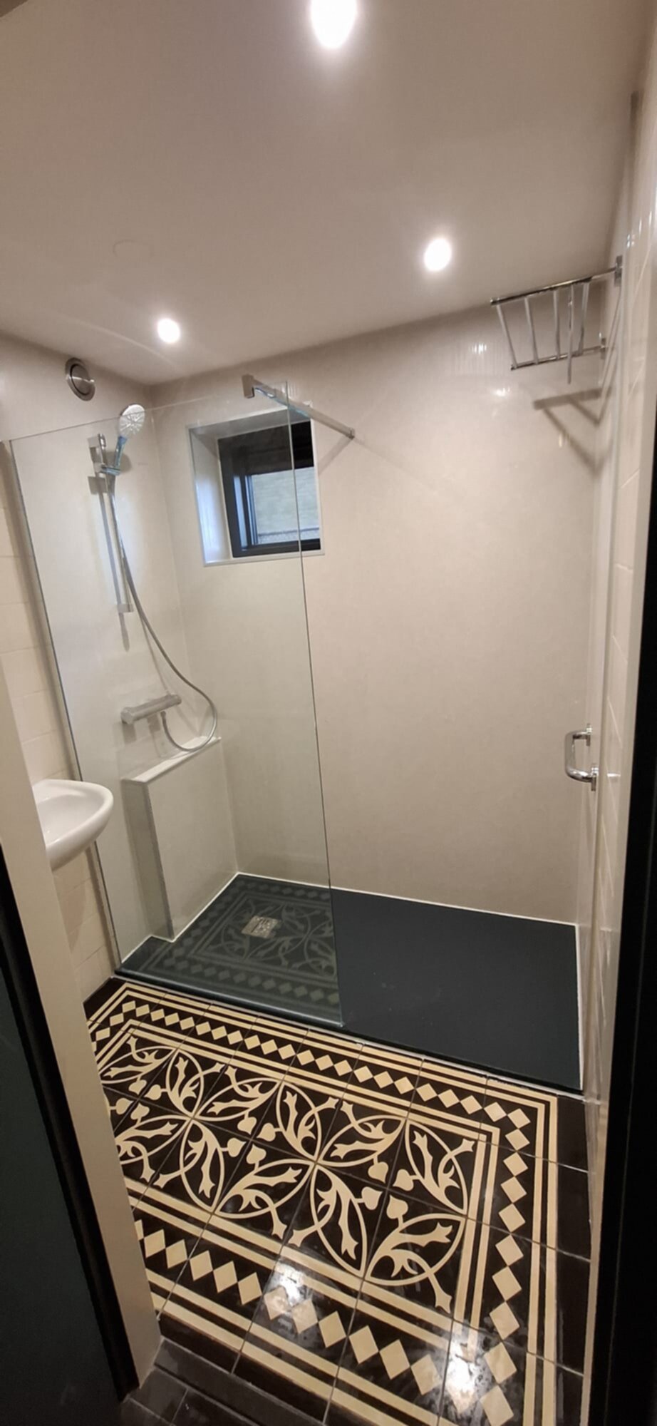 Douche met glazen schuifdeur en betegelde vloer in zwart en beige