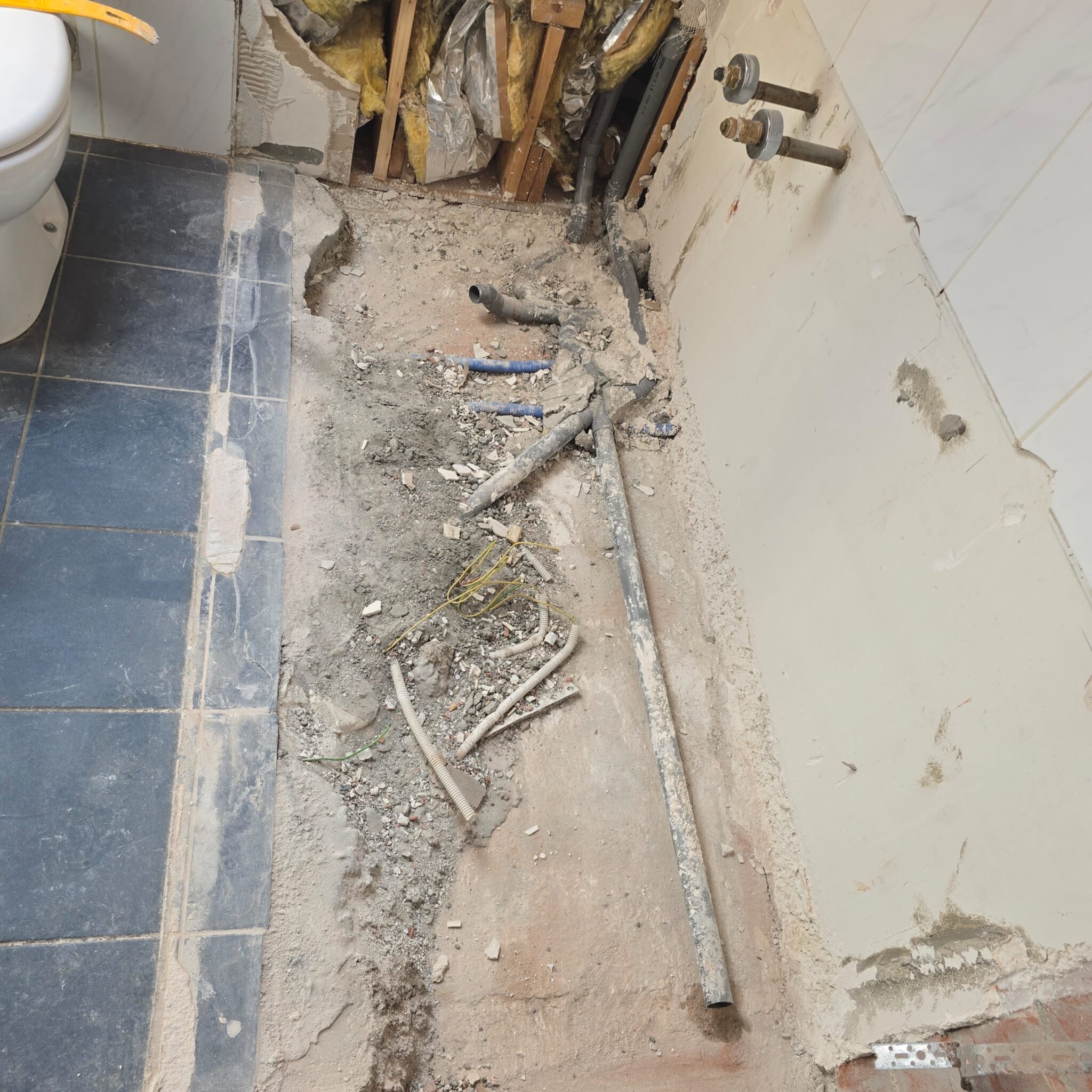 Sloop badkamer vloer met zicht op leidingen en rioleringsbuizen