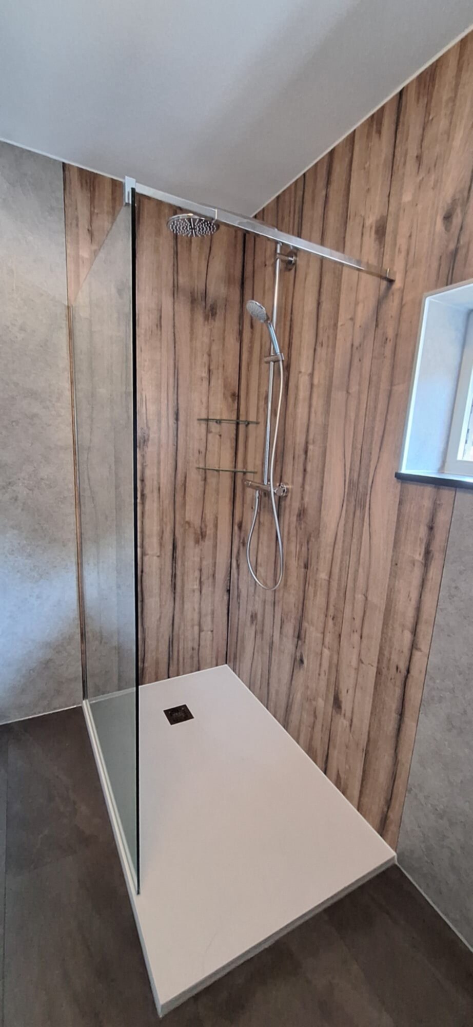 Douchecabine met glazen wand en houten panelen op de wand