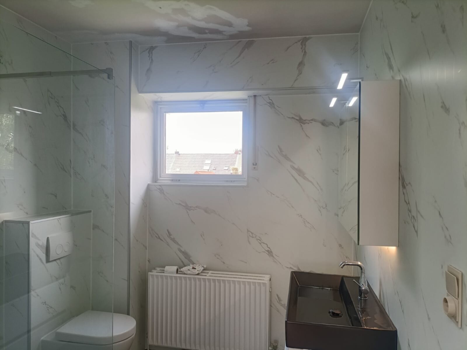 Marmer-look betegelde badkamer met toilet, douche en wasbak