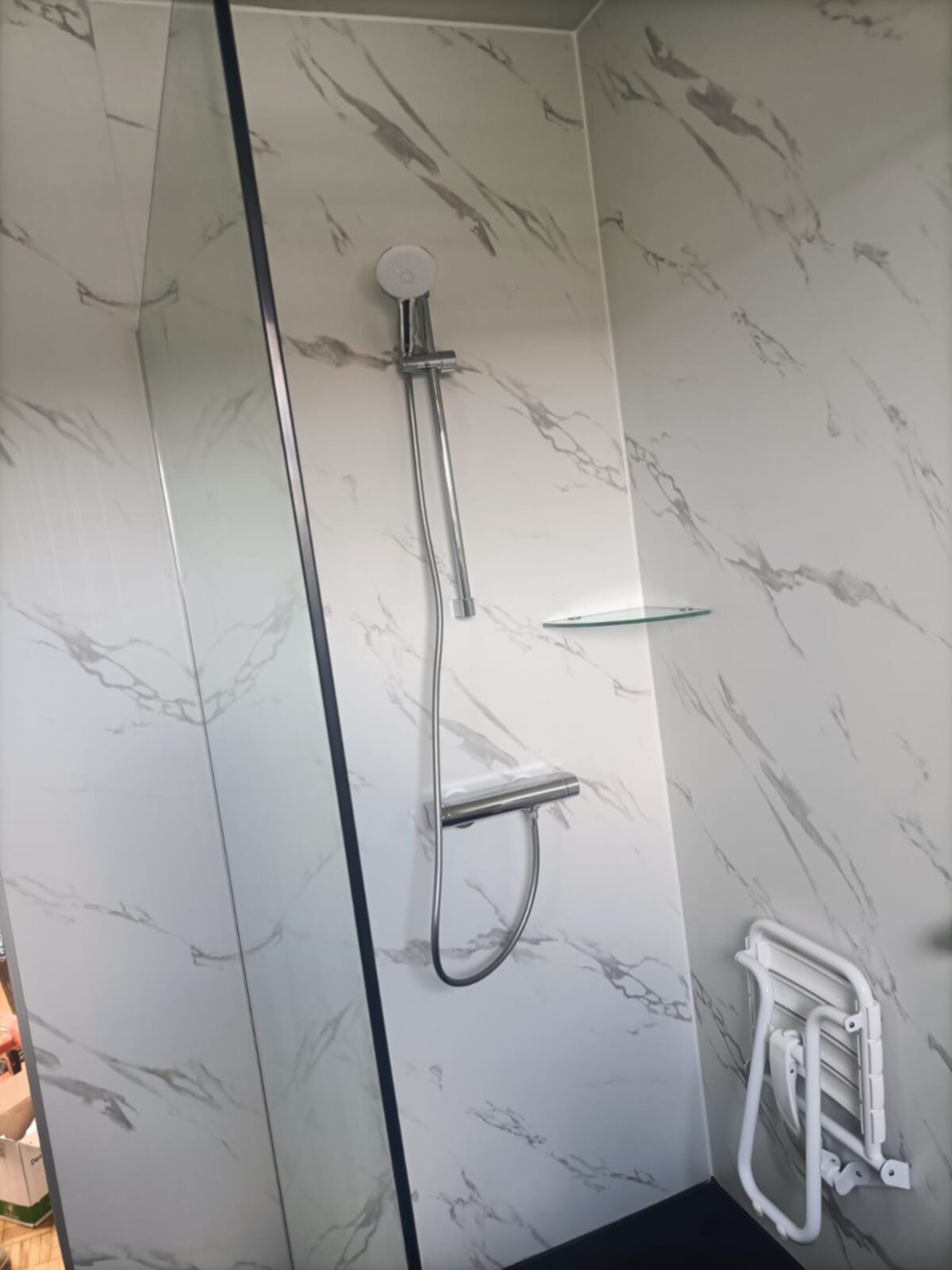 Douche met marmerlook tegels en een witte betegelde greep
