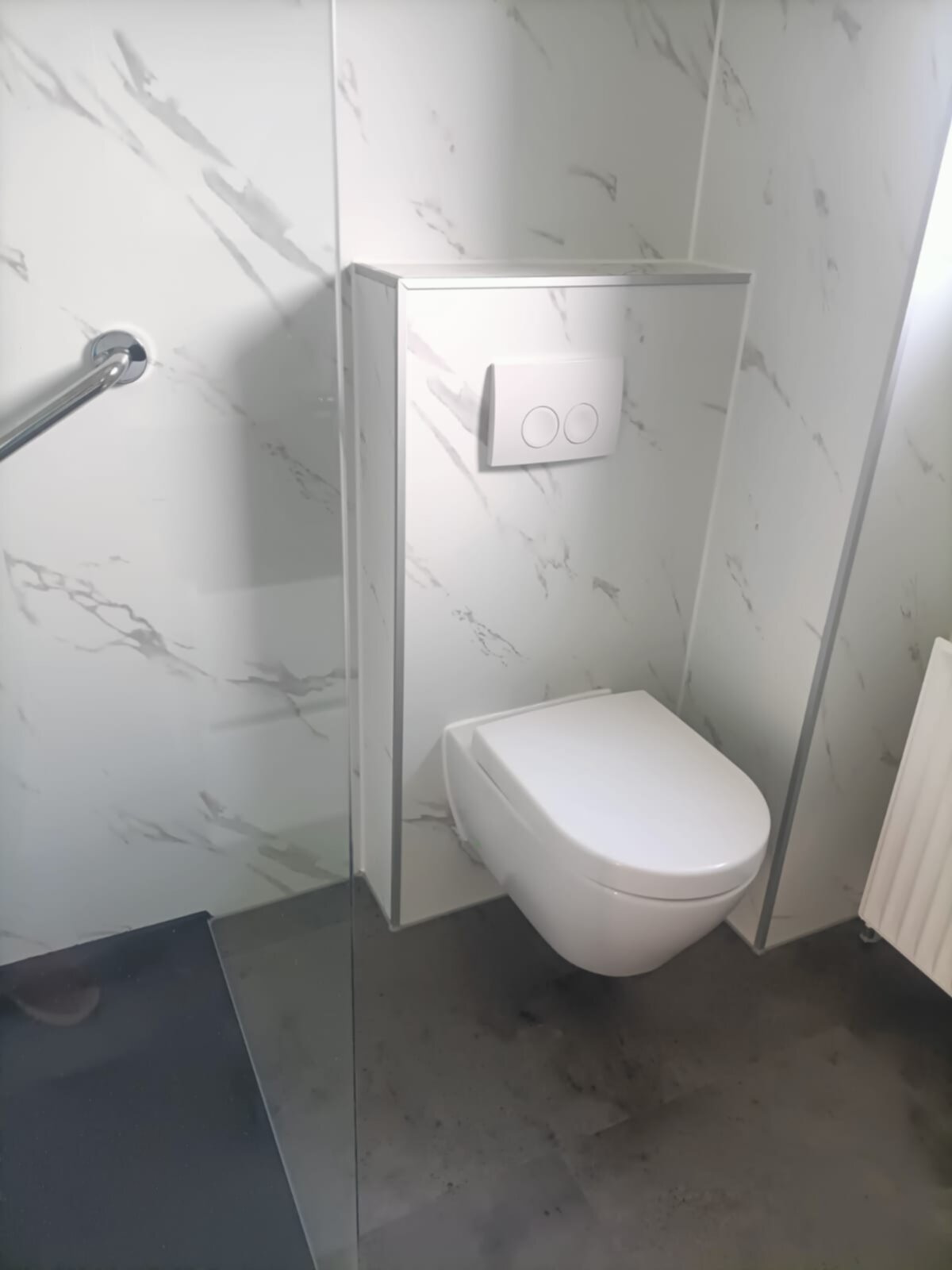 Moderne witte toilet in een badkamer met marmerlook tegels en grijze vloer
