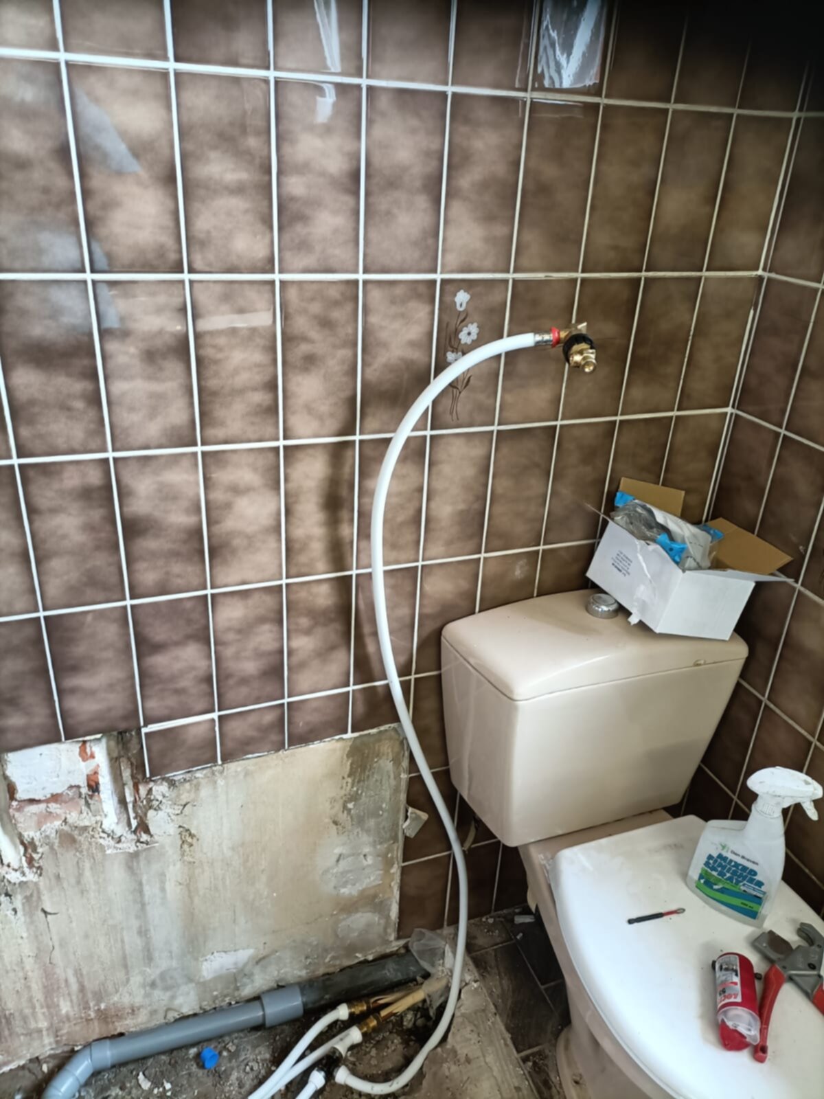 Badkamer tijdens renovatie met bruine tegels en toilet
