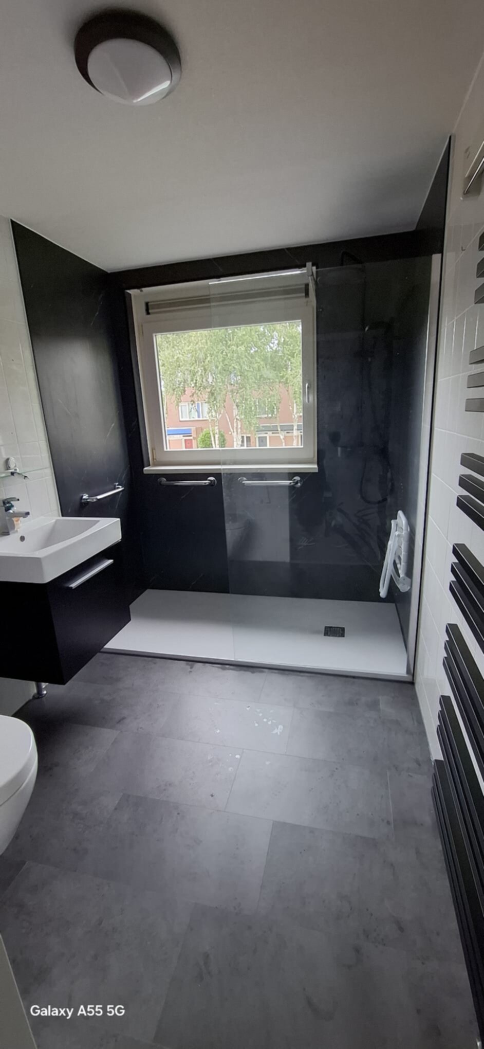 Moderne badkamer met zwarte en witte tegels, grijs toilet en wastafel