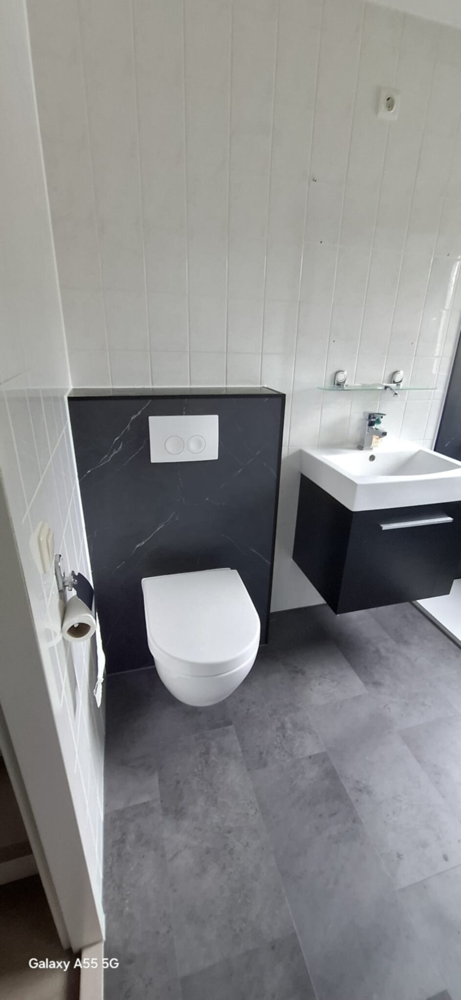 Moderne badkamer met witte toilet en wasbak, zwarte en grijze tegelwerk