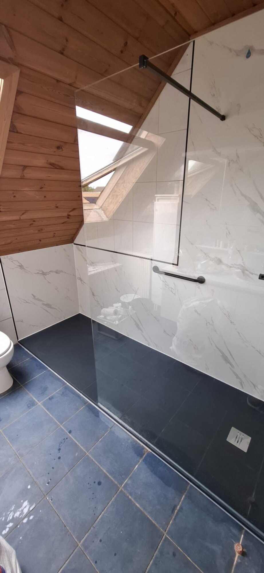 Douchecabine met glazen wand en marmeren tegelwerk in een moderne badkamer