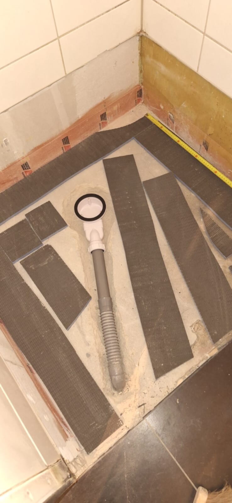 Badkamer renovatie, betegelde vloer in aanbouw met afvoer en bruine tegels