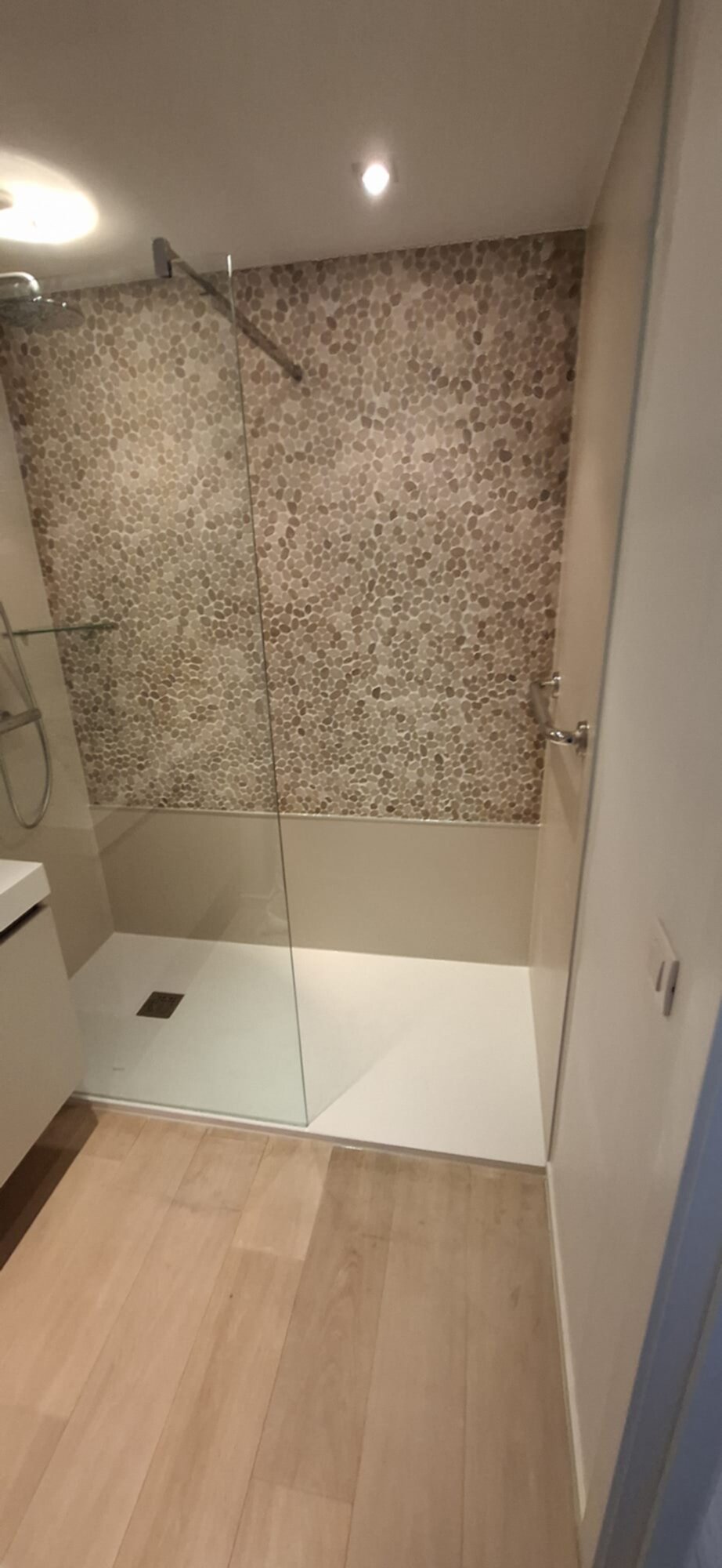 Douchecabine met glazen wand en kiezelsteen-look tegelwand