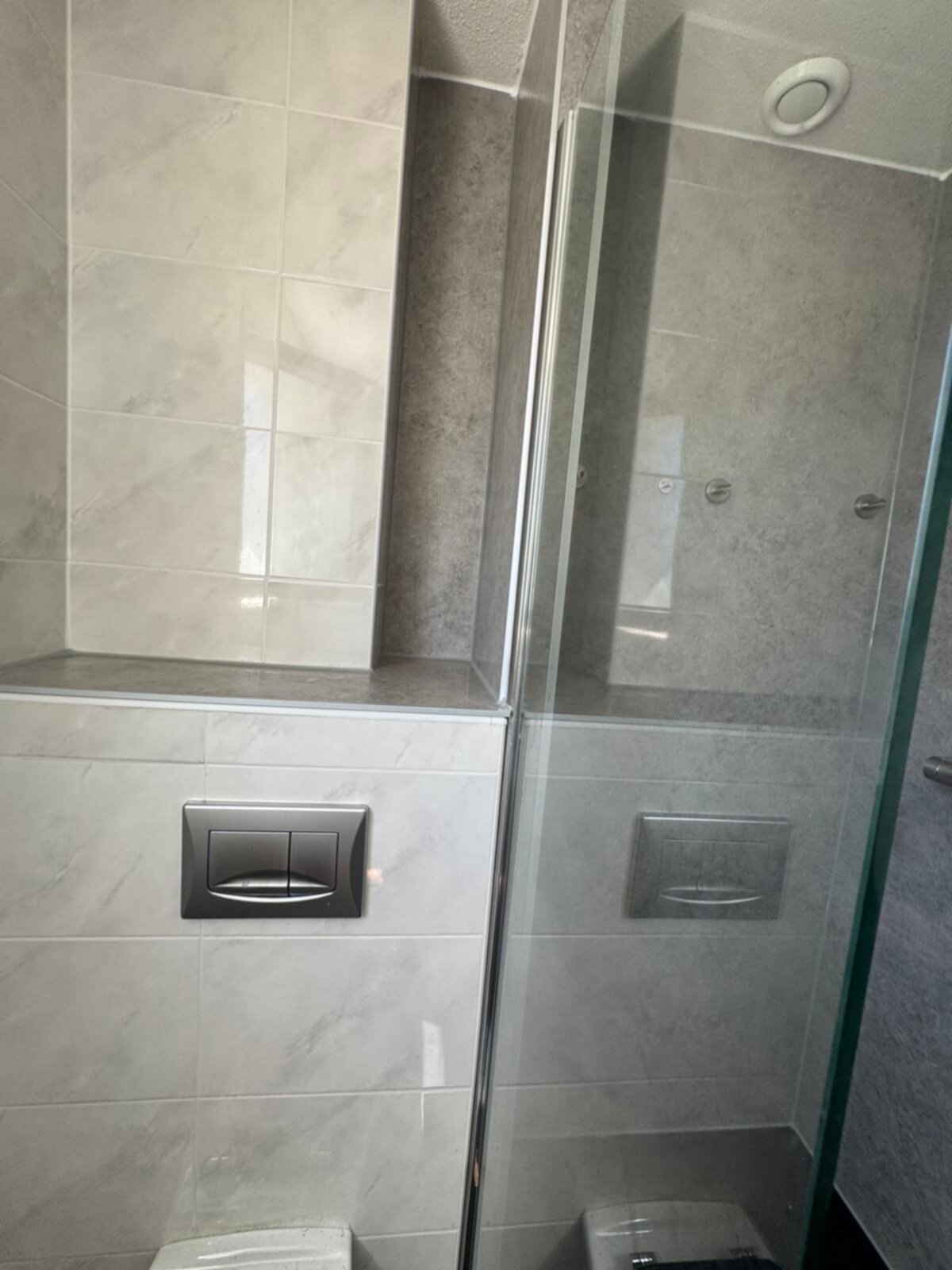 Douche met glazen schuifdeur en betegelde wanden in marmerlook